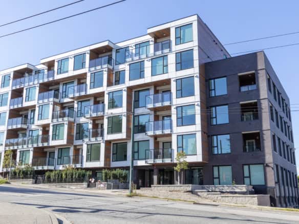 Modern multi-story residential building with large glass windows and balconies, showcasing contemporary architecture and urban living in Vancouver, British Columbia.