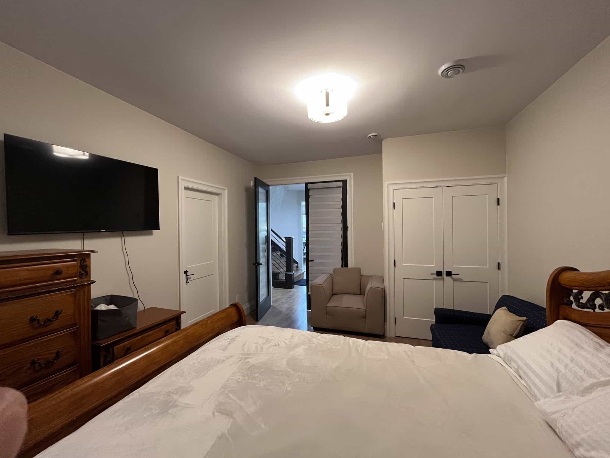 Bright modern bedroom with white walls, wooden furniture, flat-screen TV, and cozy seating, ideal for Vancouver Island real estate and property rentals by Orca Realty Inc.