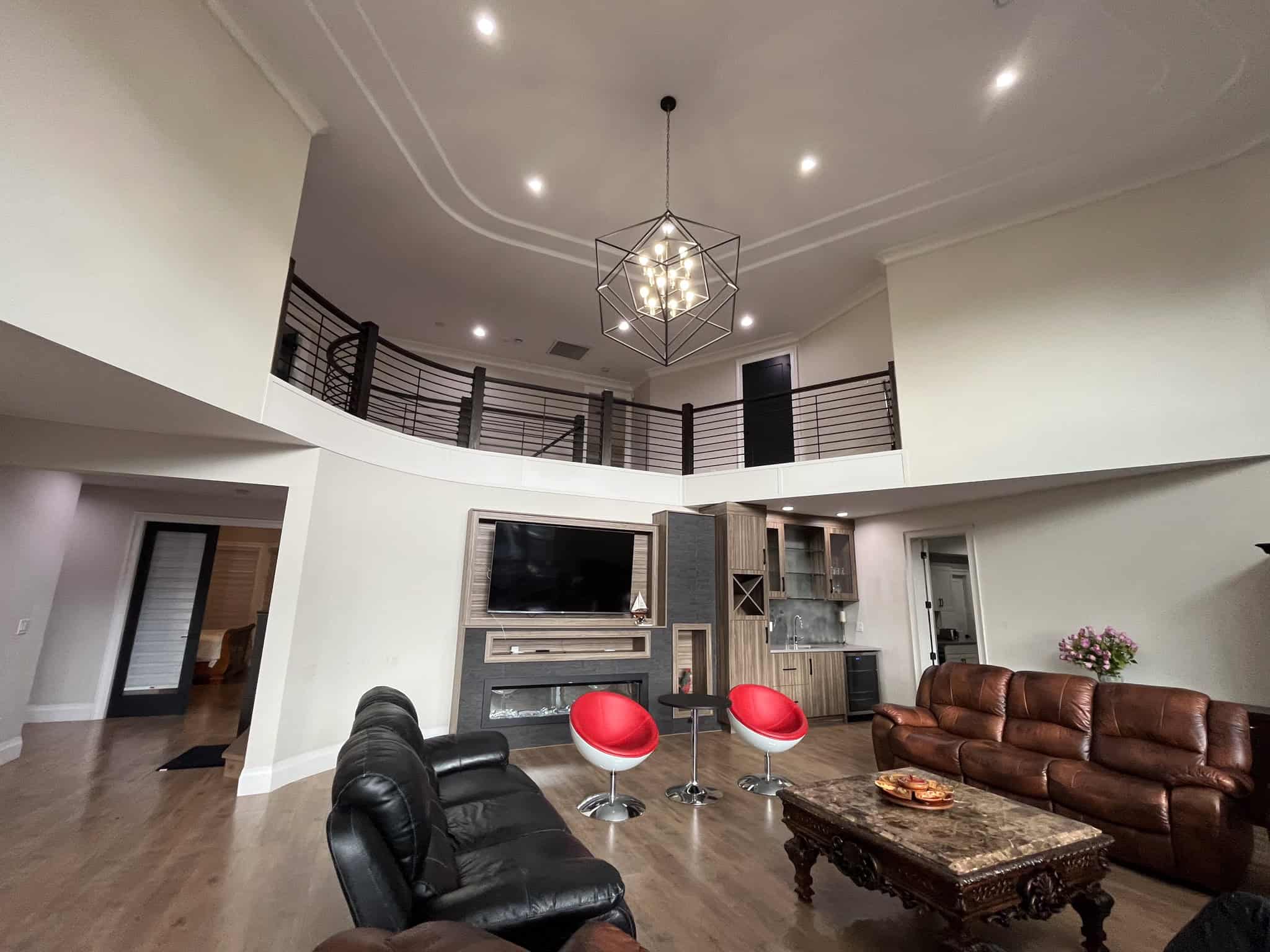 Spacious modern living room with high ceilings, contemporary lighting fixture, and a cozy fireplace, perfect for comfortable Vancouver Island real estate living and showcasing premium residential properties.