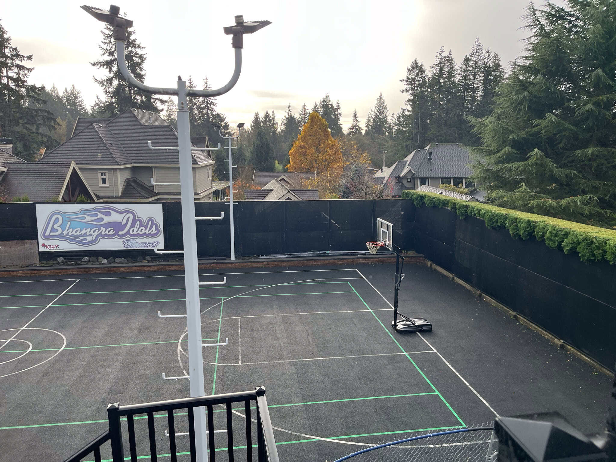 Bright outdoor basketball court surrounded by trees and residential houses, ideal for family fun and recreation in Vancouver's scenic neighborhoods.
