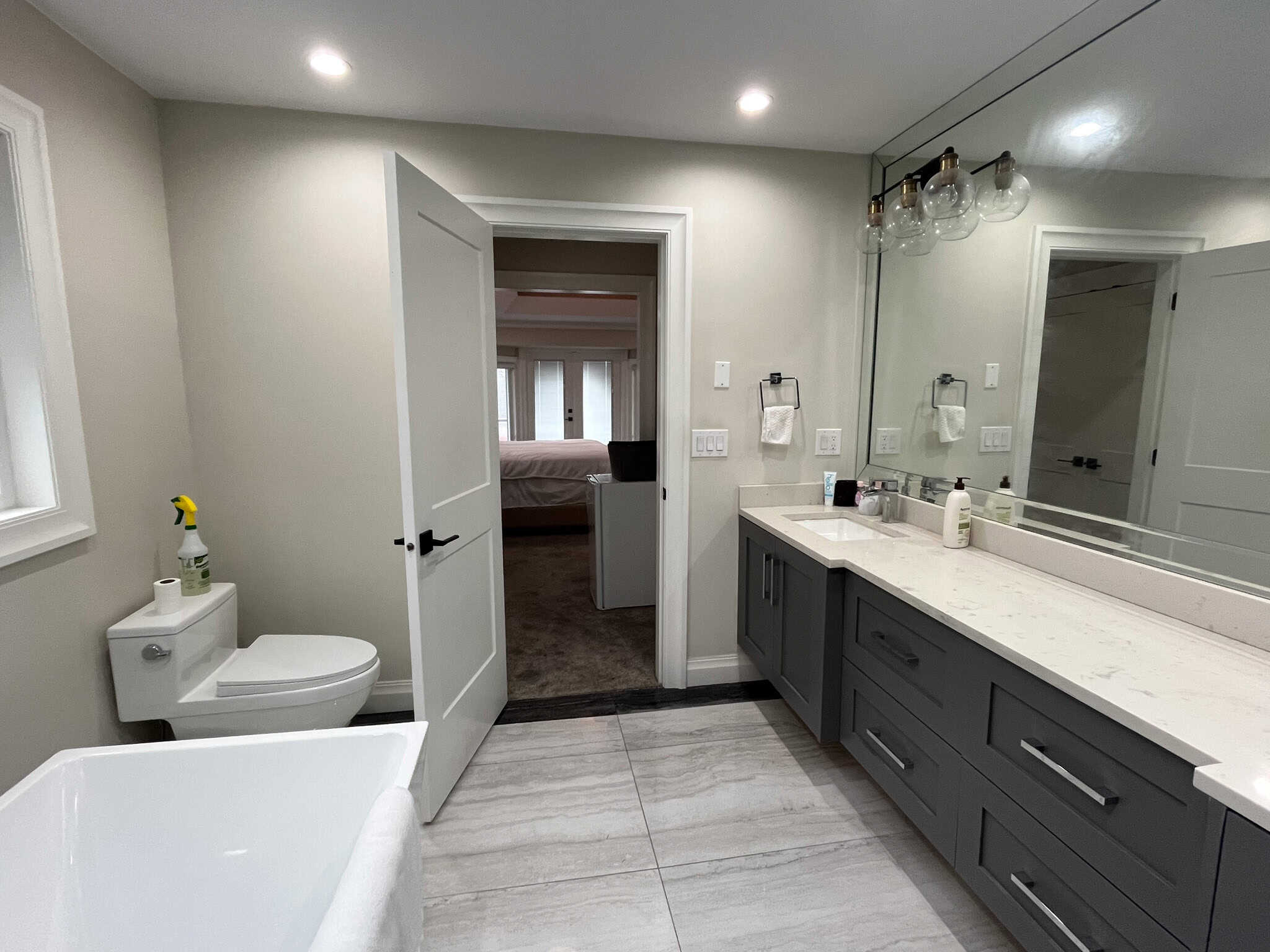 Modern grey and white bathroom with large mirror, sleek vanity, and contemporary lighting fixtures at Orca Realty Inc. in BC. Ideal for homebuyers seeking stylish real estate options.