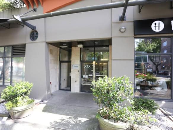 Modern commercial office building exterior at 828 with large glass doors and potted plants for curb appeal.