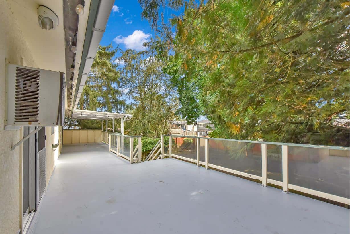 Spacious apartment balcony with privacy glass railings and lush greenery, ideal for outdoor living and entertaining in Vancouver, BC.