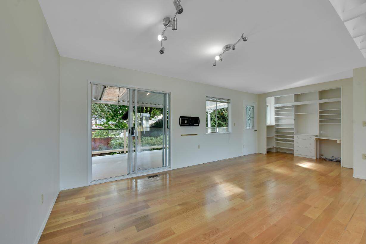 Spacious living room with sliding glass door leading to a balcony, hardwood floors, and built-in shelves providing ample space for family and relaxation.