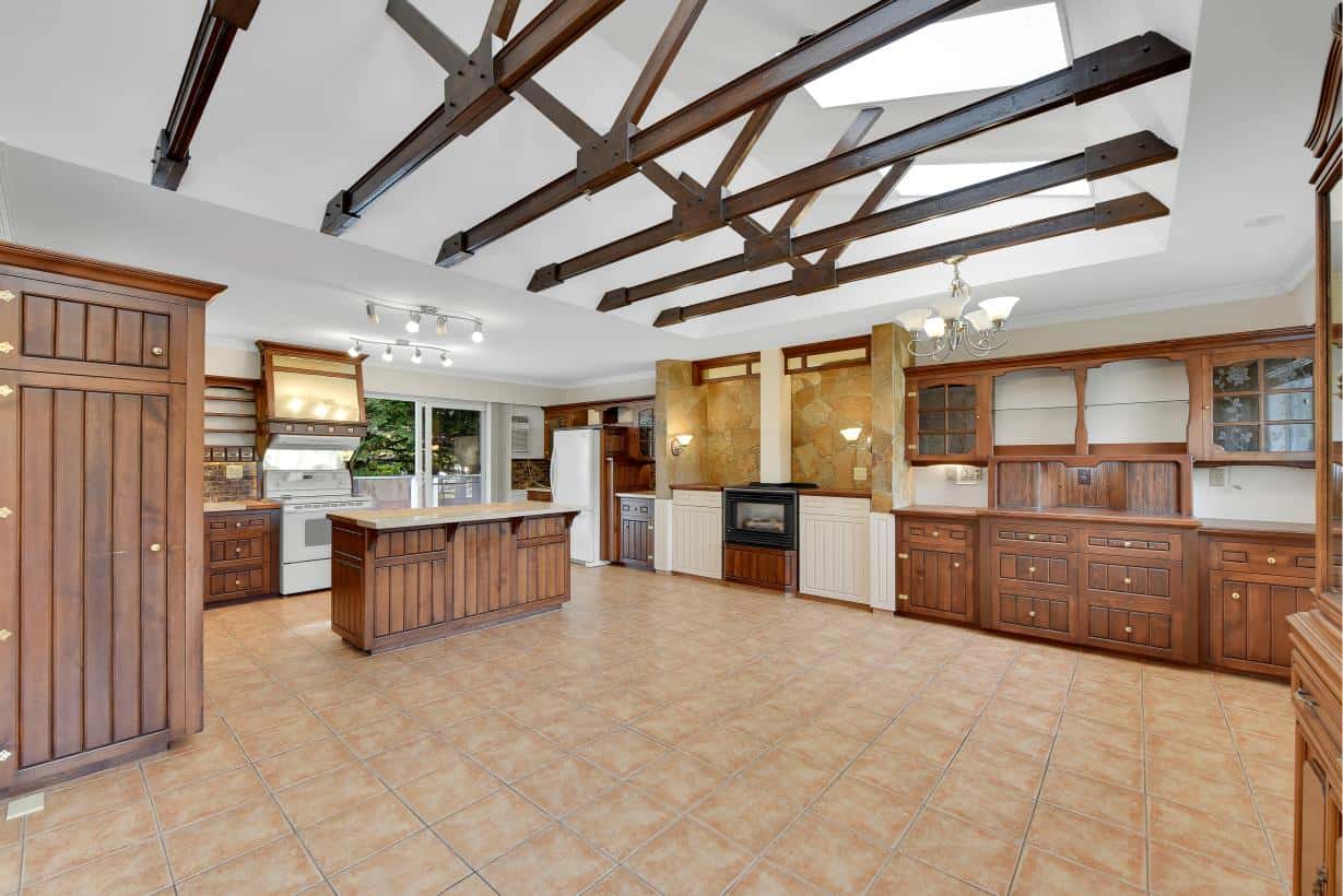 Bright spacious kitchen with rustic wooden cabinetry, tiled flooring, and exposed roof beams, perfect for Ontario real estate buyers seeking a charming and functional home.