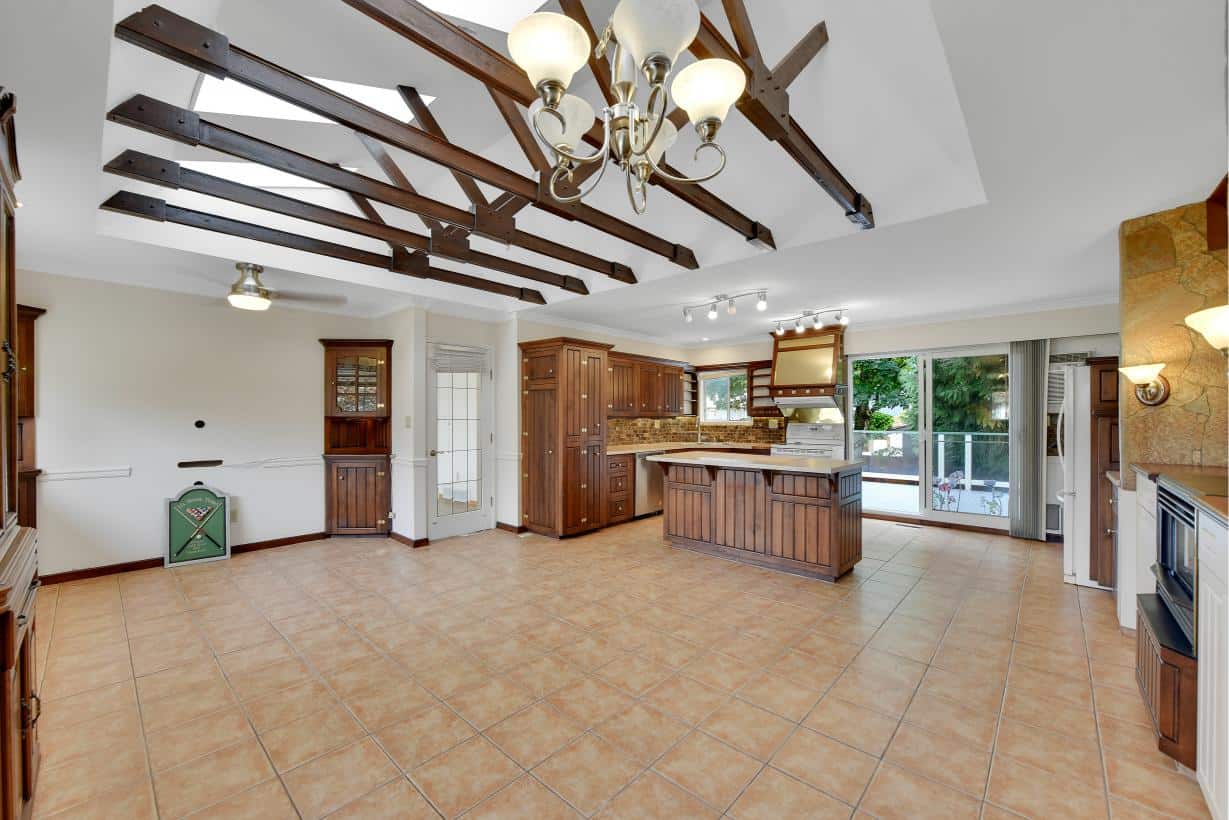 Spacious kitchen and living area with wooden cabinetry, tiled flooring, and large glass sliding doors opening to a backyard patio, ideal for Vancouver homebuyers seeking a family-friendly space.