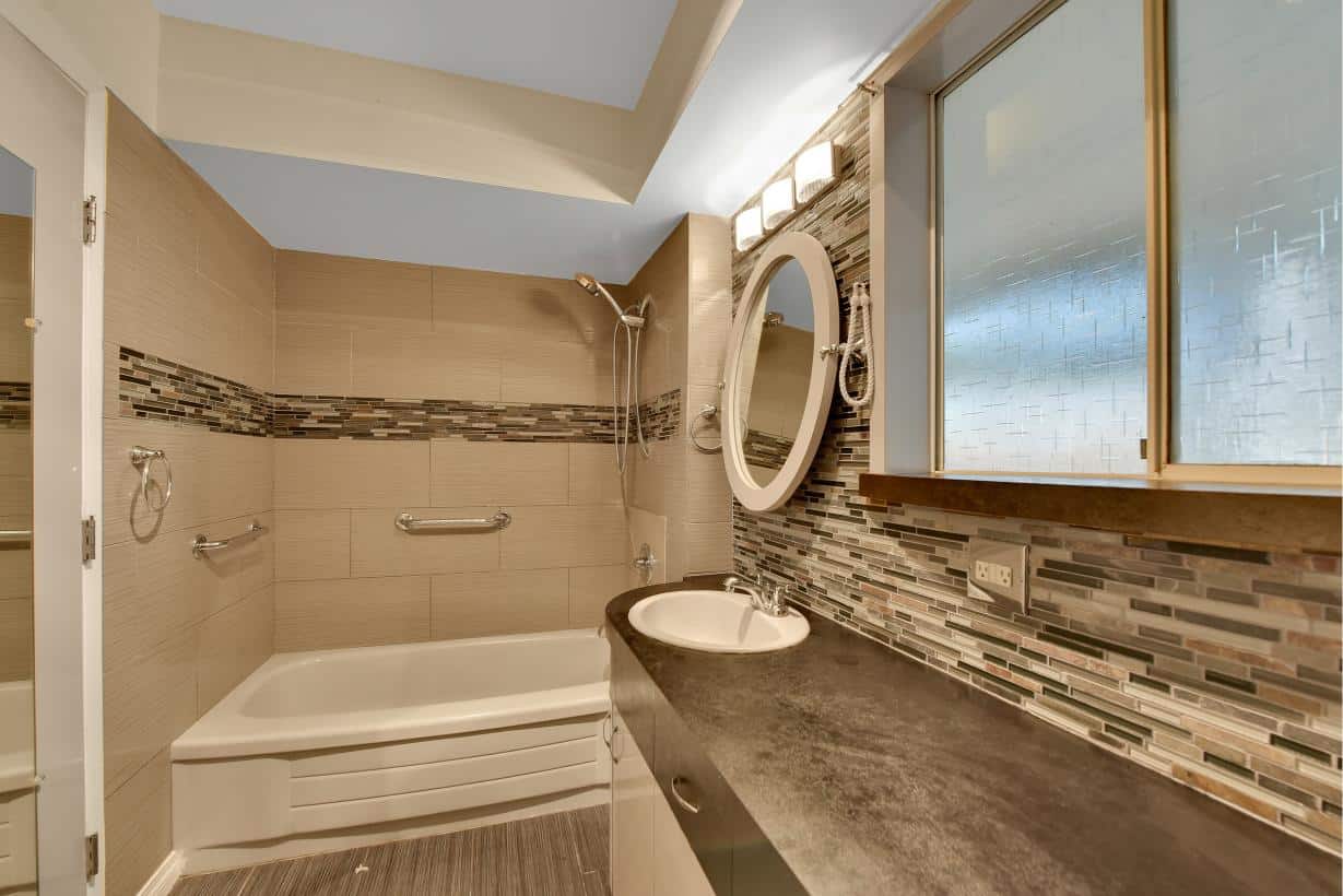 Modern bathroom with beige tiles, glass window, and contemporary fixtures, perfect for Vancouver homes.