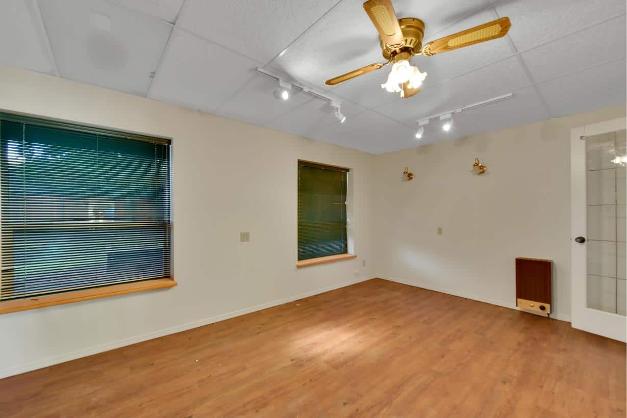 Spacious living room with hardwood flooring, ceiling fan, ample natural light from large windows, and neutral wall colors, ideal for home staging or real estate listings in Vancouver.