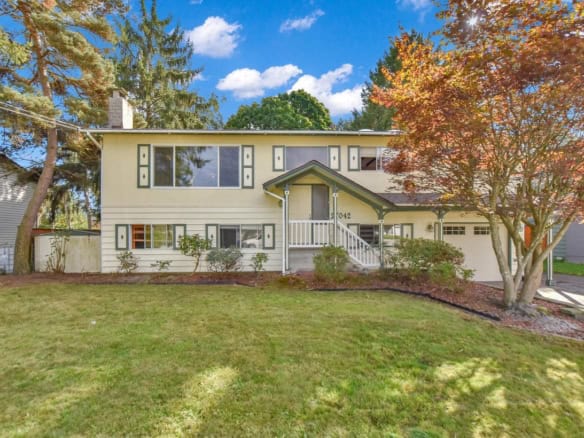 Spacious two-storey family home with a charming front yard, surrounded by mature trees and lush landscaping, located in a desirable neighbourhood served by Orca Realty Inc.