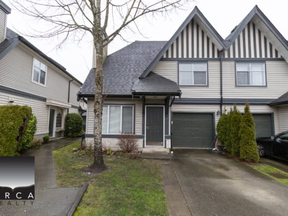Spacious townhouse with modern exterior, attached garage, front yard, and lush landscaping, ideal for Vancouver housing market, offered by Orca Realty Inc. in BC.