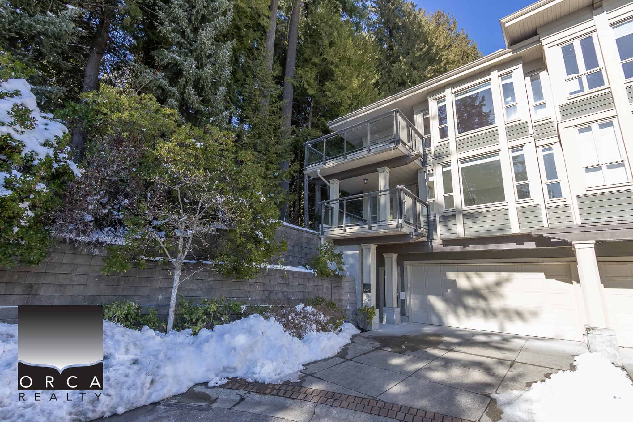 Spacious modern townhouse with multiple outdoor balconies, situated next to lush greenery and trees, available through Orca Realty Inc., ideal for buyers seeking a serene and contemporary residential property in BC.