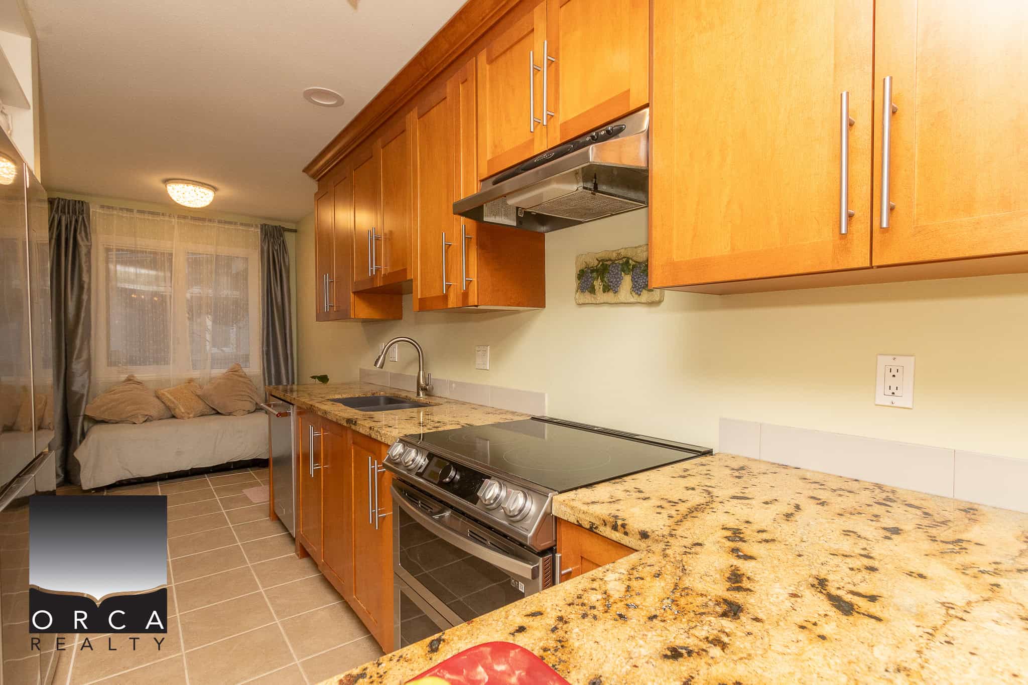 Stunning modern kitchen with warm wooden cabinetry, granite countertops, stainless steel appliances, and a cozy sitting area by the window, perfect for Vancouver Island real estate buyers.