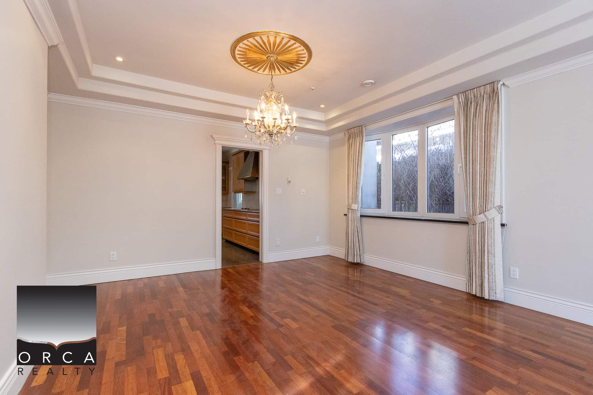 10 Bright spacious dining room with hardwood flooring, elegant chandelier, large window with curtains, and open view to kitchen, ideal for Vancouver homebuyers seeking stylish interior spaces.