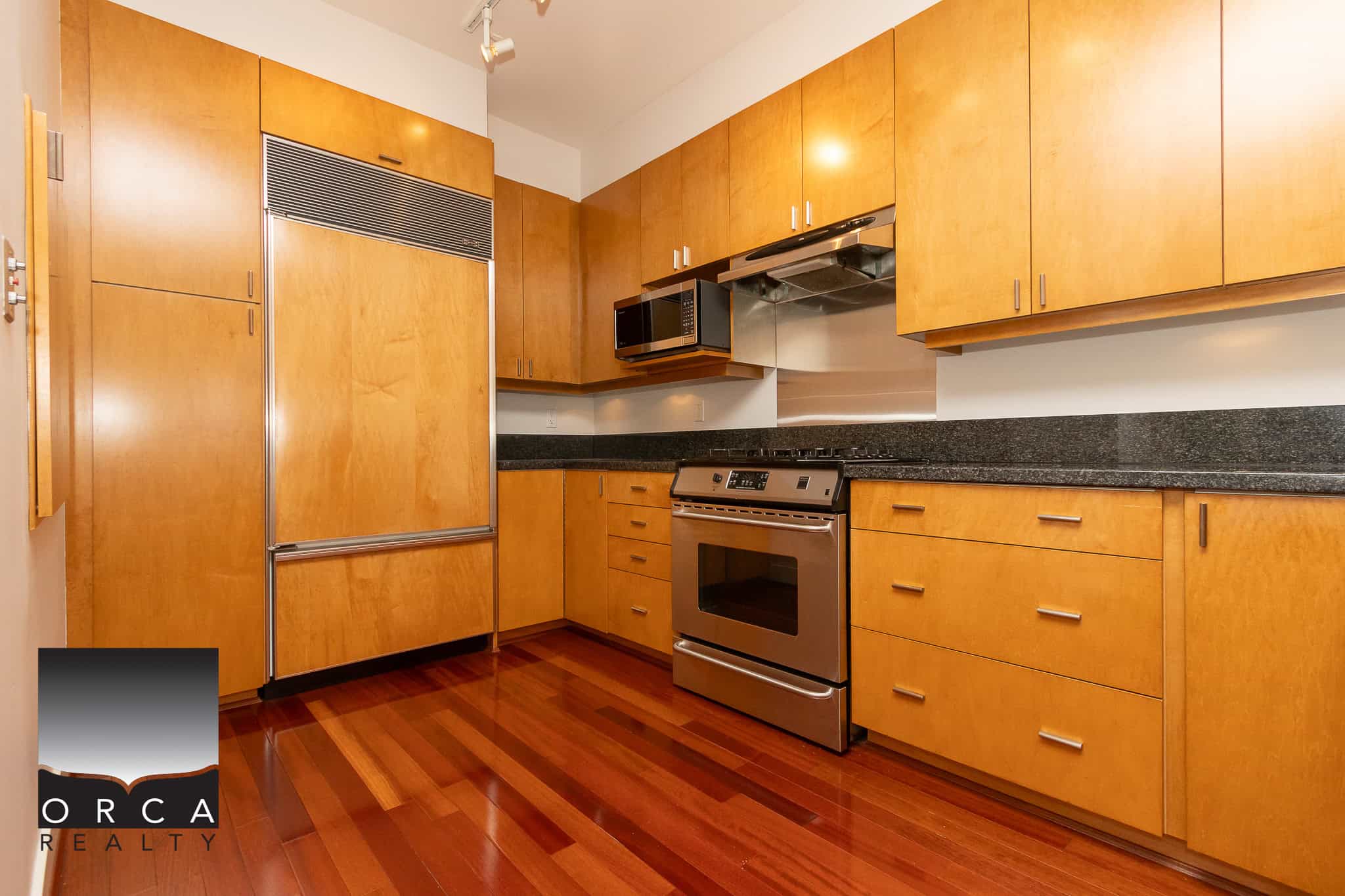Modern kitchen with stainless steel appliances and warm wood cabinetry, ideal for homebuyers seeking contemporary Vancouver Island homes.
