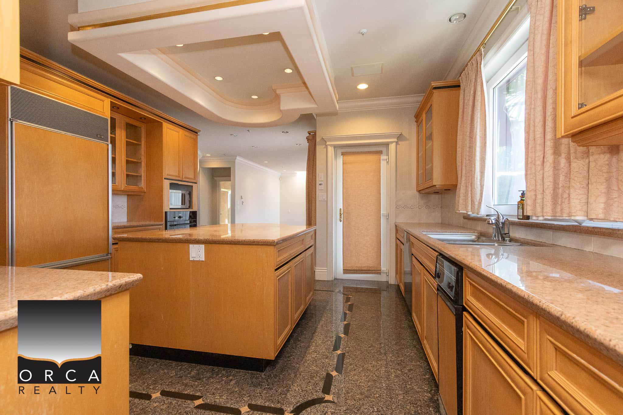11 Spacious kitchen with warm wooden cabinetry and granite countertops, featuring modern appliances and natural light from large windows, perfect for family living and entertaining.
