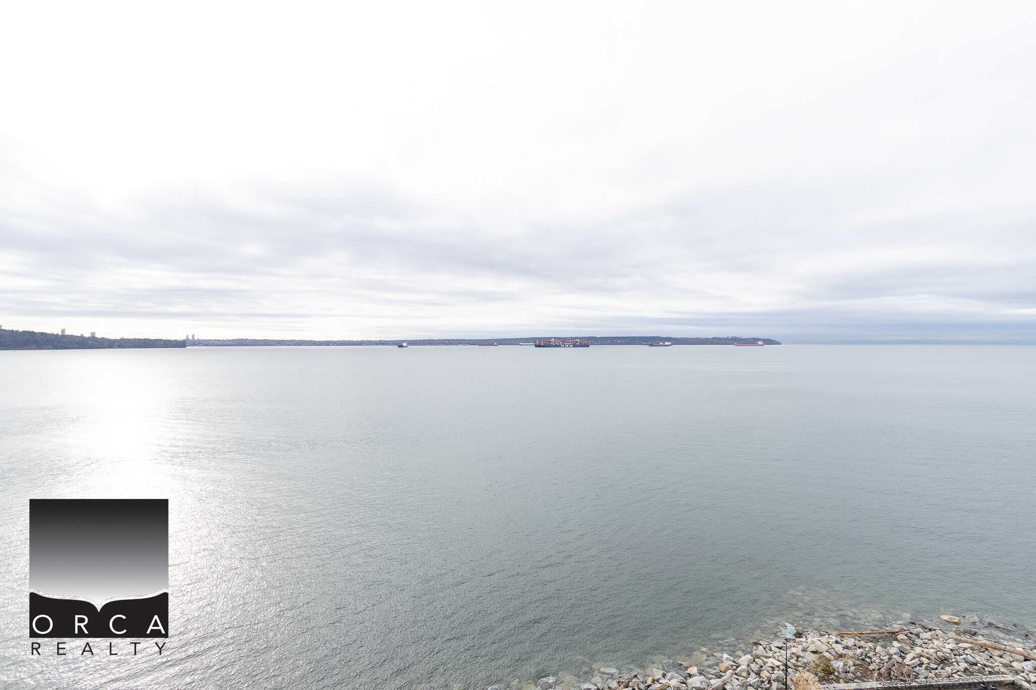 Tranquil ocean view with ships sailing on open water, showcasing coastal property appeal and waterfront living in Vancouver, BC. Perfect for real estate marketing by Orca Realty Inc.