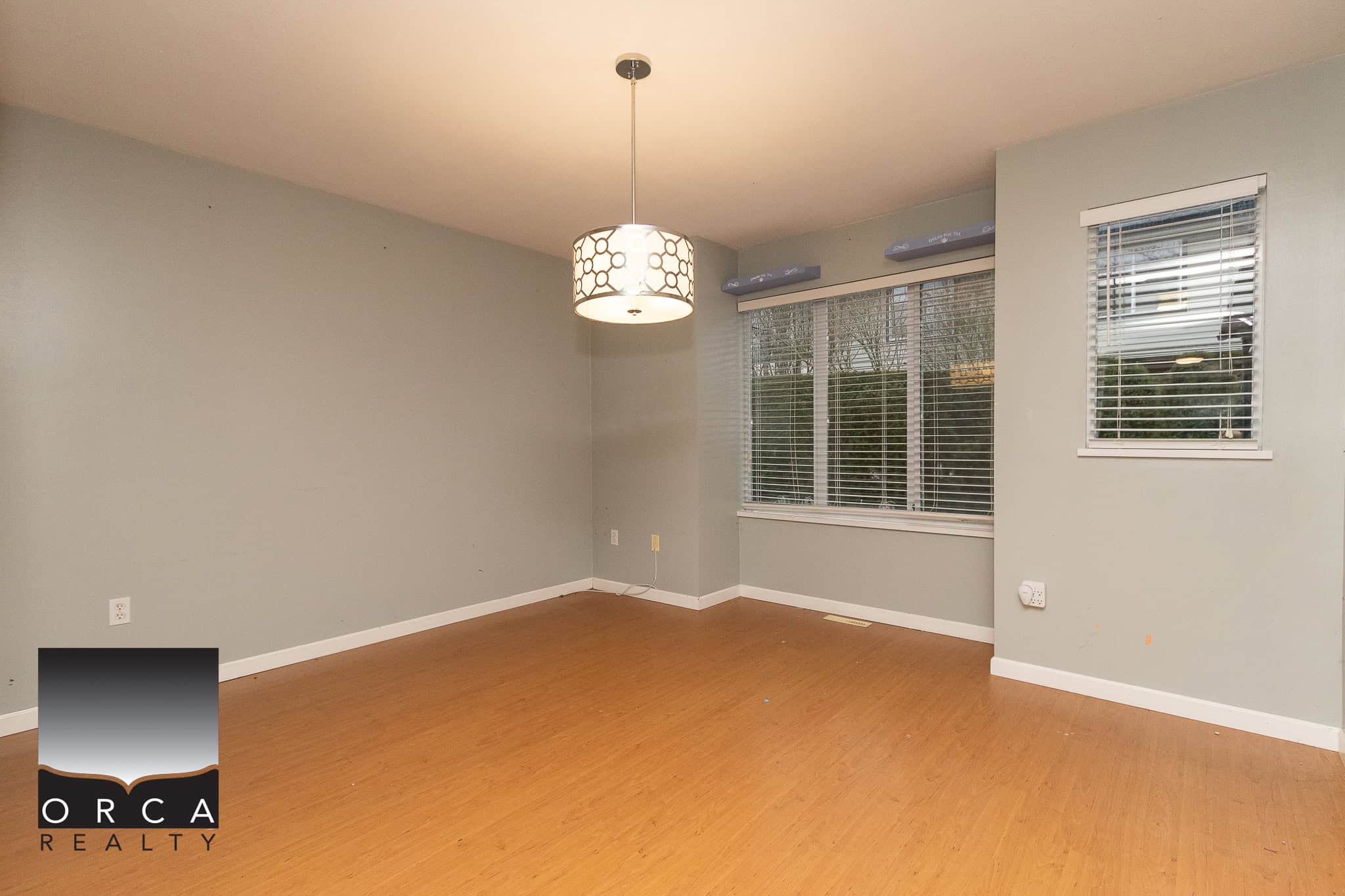 Bright living room with large windows and hardwood flooring, showcasing a modern interior design by Orca Realty Inc. Perfect for Vancouver homebuyers seeking spacious, well-lit homes.