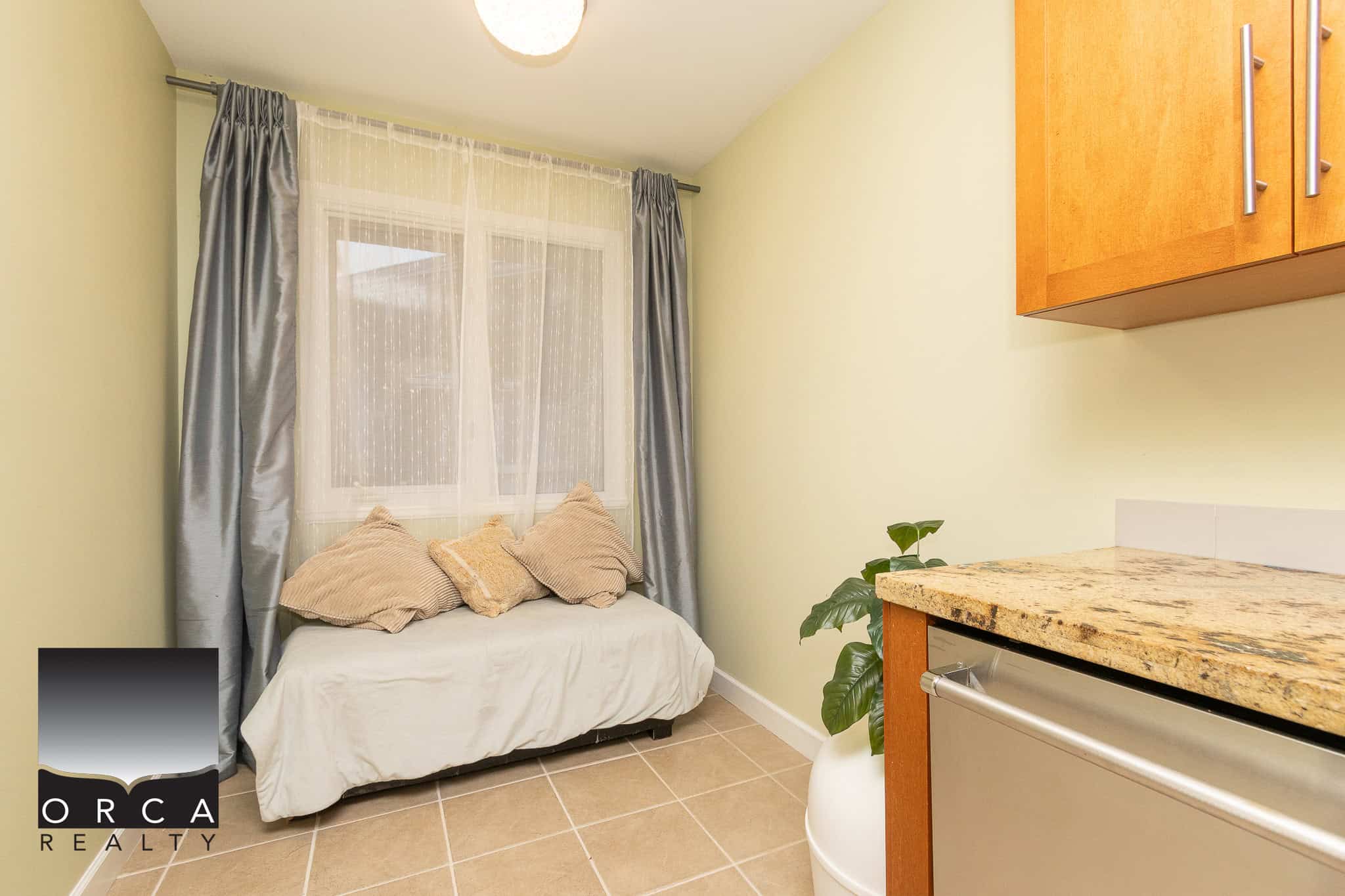 Cozy indoor space with a window seat, beige cushions, and natural light, showcasing a part of a kitchen or living area in a modern home listed by Orca Realty Inc.