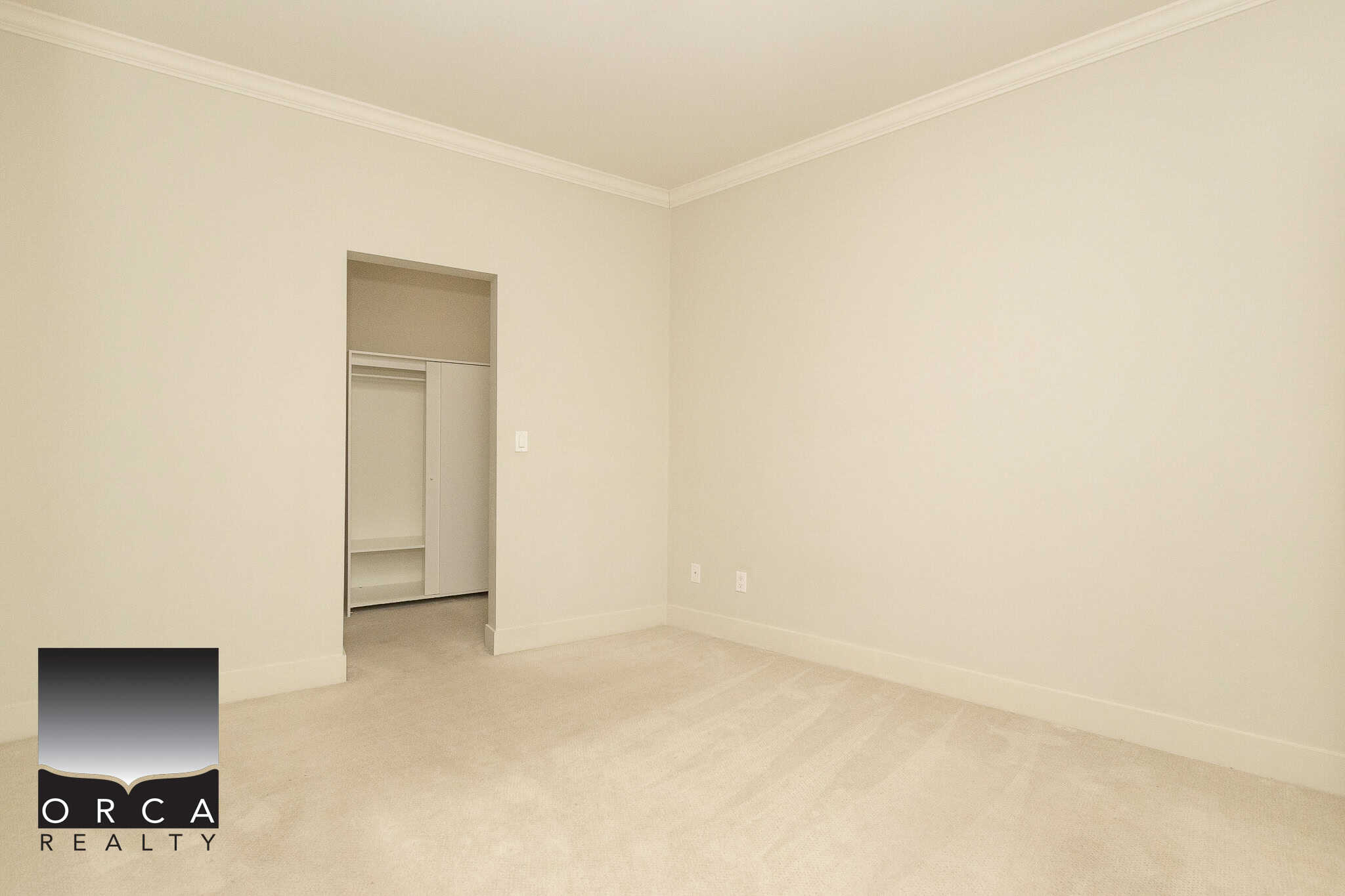 Bright empty bedroom with neutral walls, carpeting, and a walk-in closet, showcasing a spacious, move-in ready property listed by Orca Realty Inc.