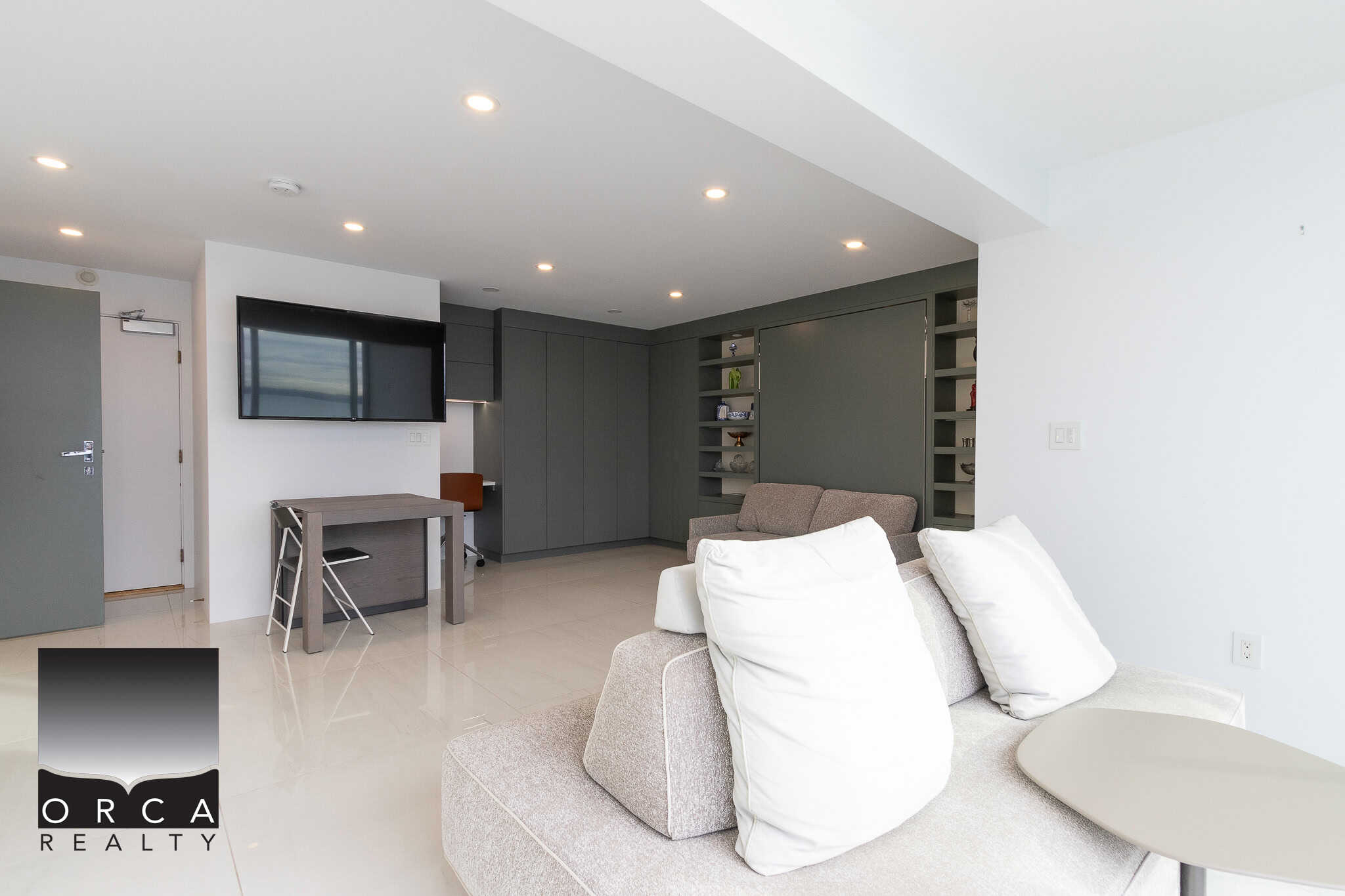 Modern open-concept living room with neutral tones, sleek cabinetry, wall-mounted TV, and comfortable seating, ideal for Vancouver Island real estate.