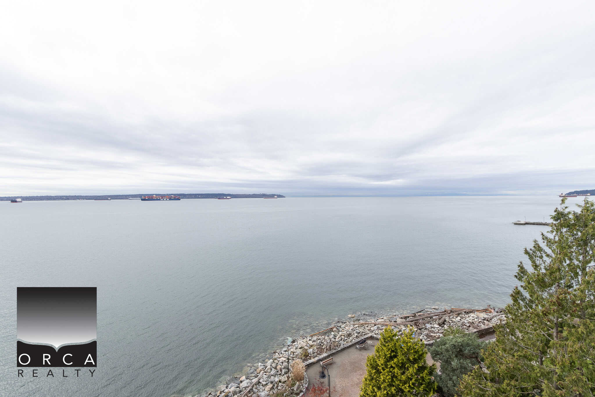 Stunning ocean view from a waterfront property in Orca Realty's listings, showcasing serene waters and maritime traffic, ideal for coastal living in Vancouver Island or surrounding areas.