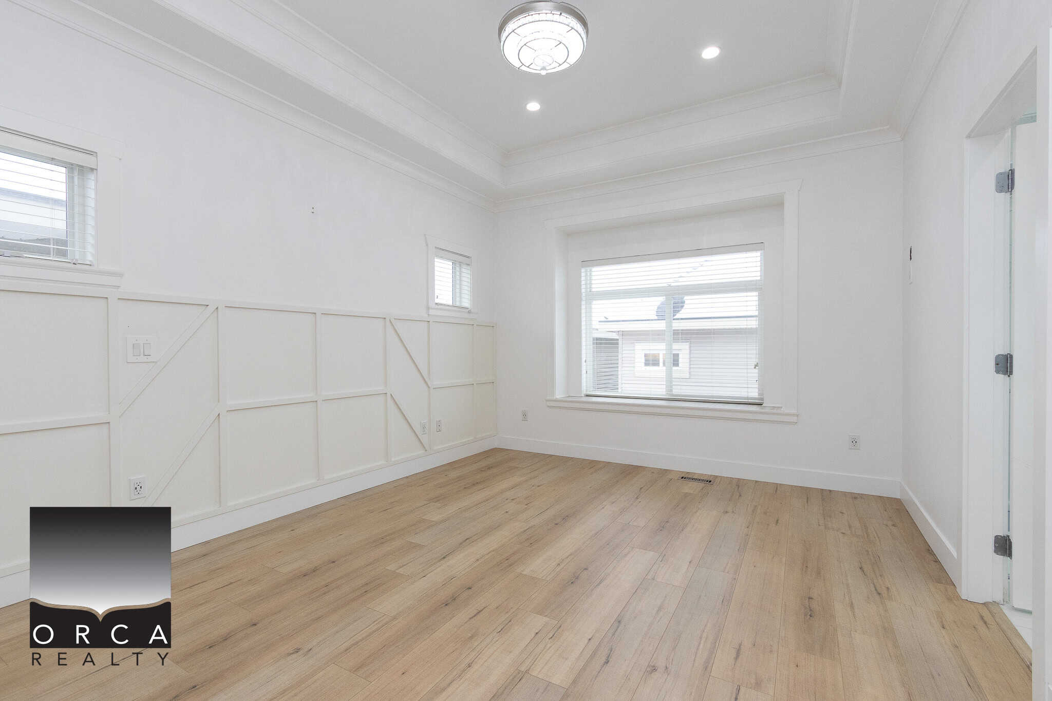 17 Bright, spacious interior room with large windows, white walls, and hardwood flooring, showcasing a modern residential space perfect for real estate listing in Vancouver by Orca Realty Inc.