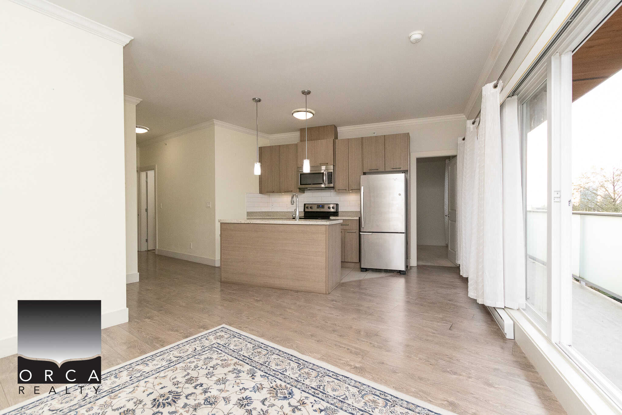 Modern open-concept kitchen with stainless steel appliances, wooden cabinetry, and access to a bright balcony, perfect for Vancouver real estate buyers seeking contemporary condos.
