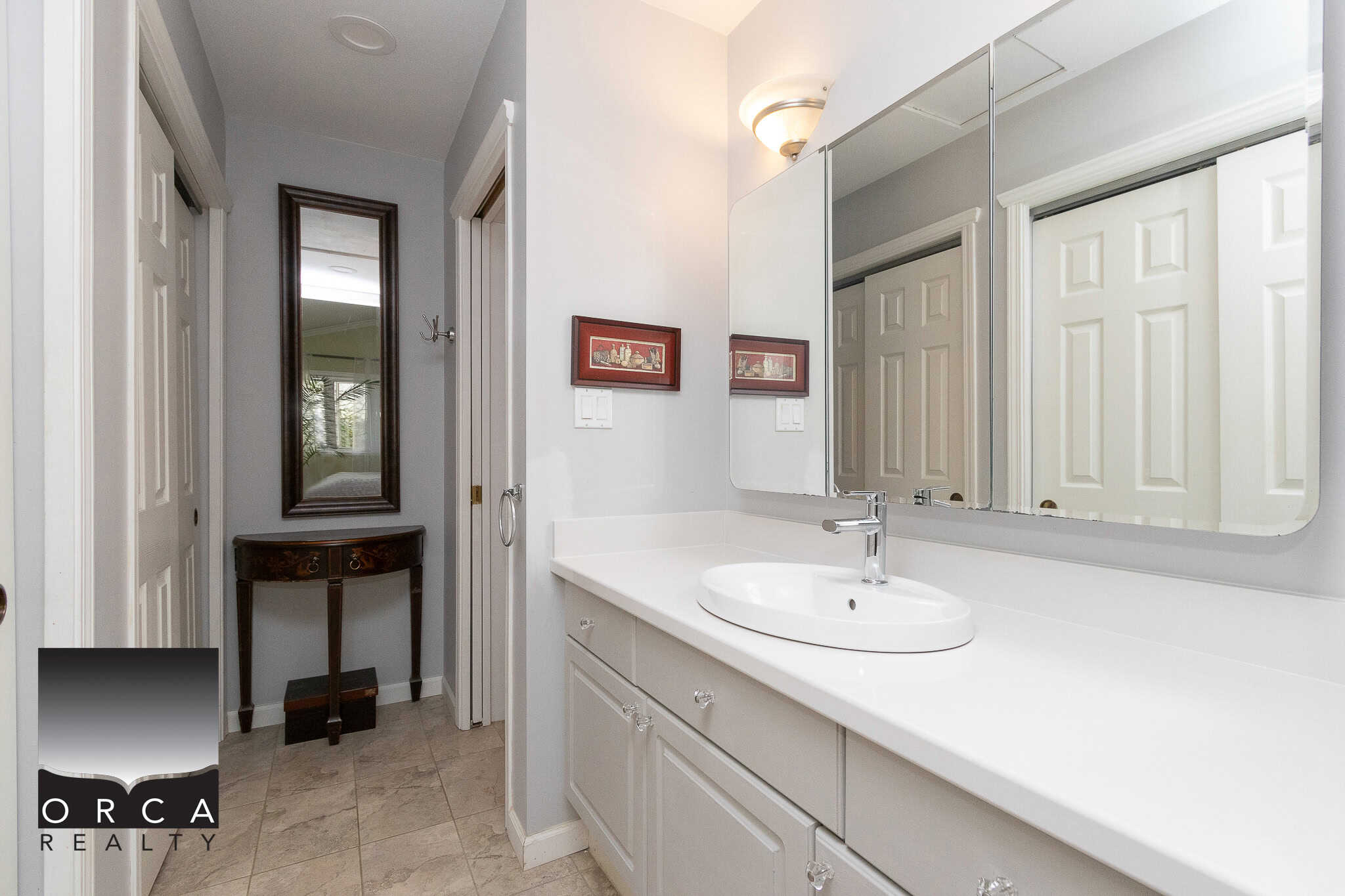 Bright bathroom with white vanity and large mirror, featuring modern fixtures and neutral tile flooring, perfect for Vancouver or BC homes.