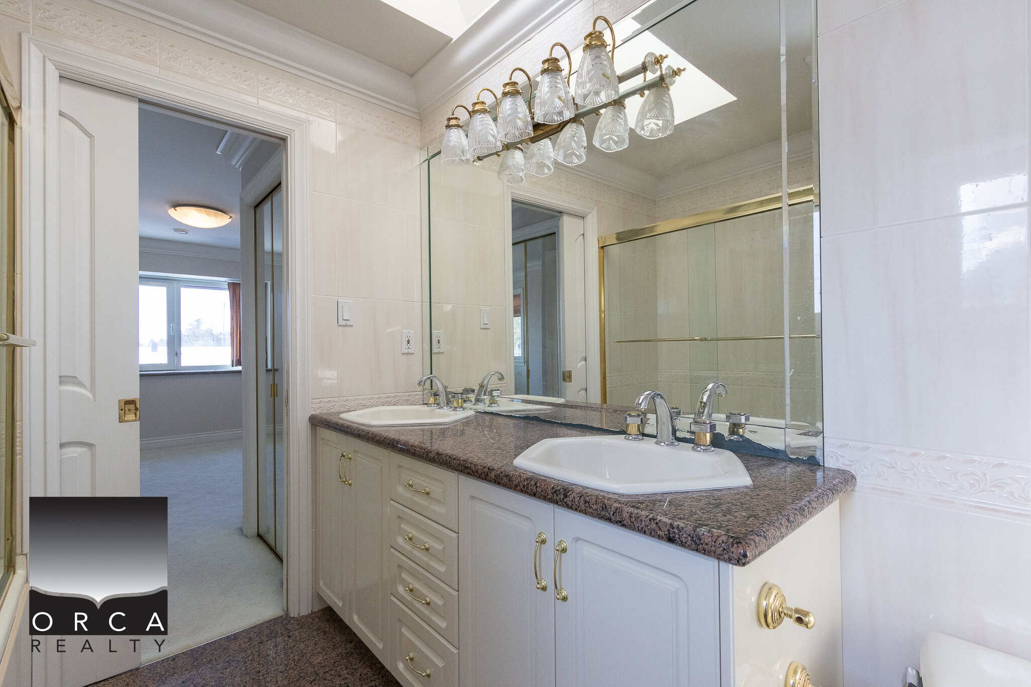 19 Bright bathroom featuring dual sinks, elegant mirror, and classic decor with gold accents, perfect for a comfortable home in BC's real estate market.
