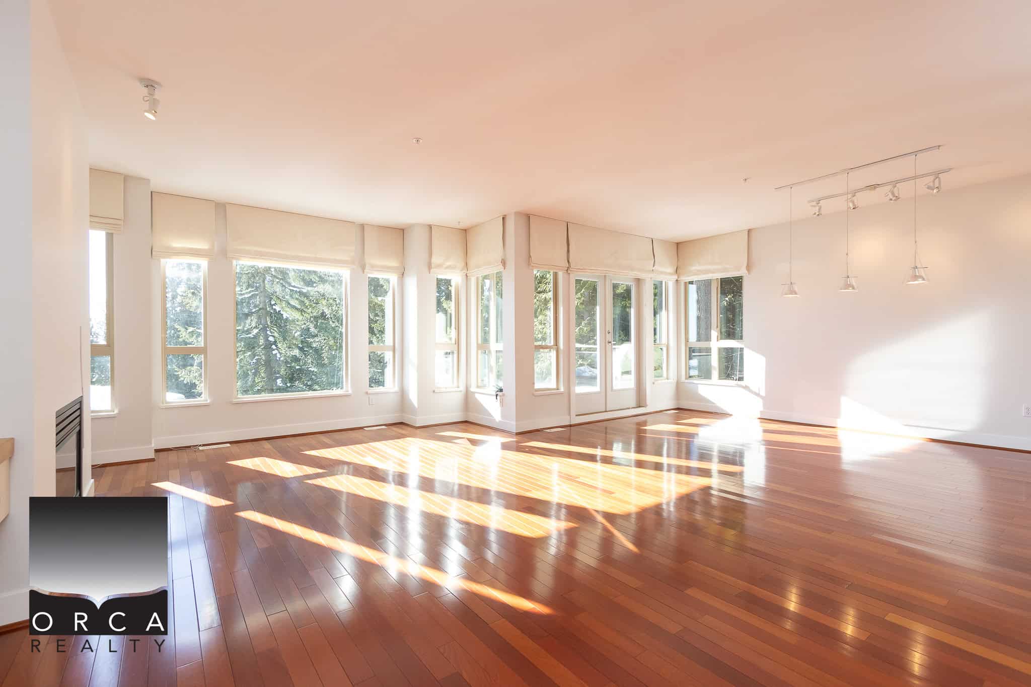 Spacious bright living room with large windows, hardwood floors, and modern lighting, ideal for Vancouver real estate buyers searching for stylish, open-concept homes in the area.
