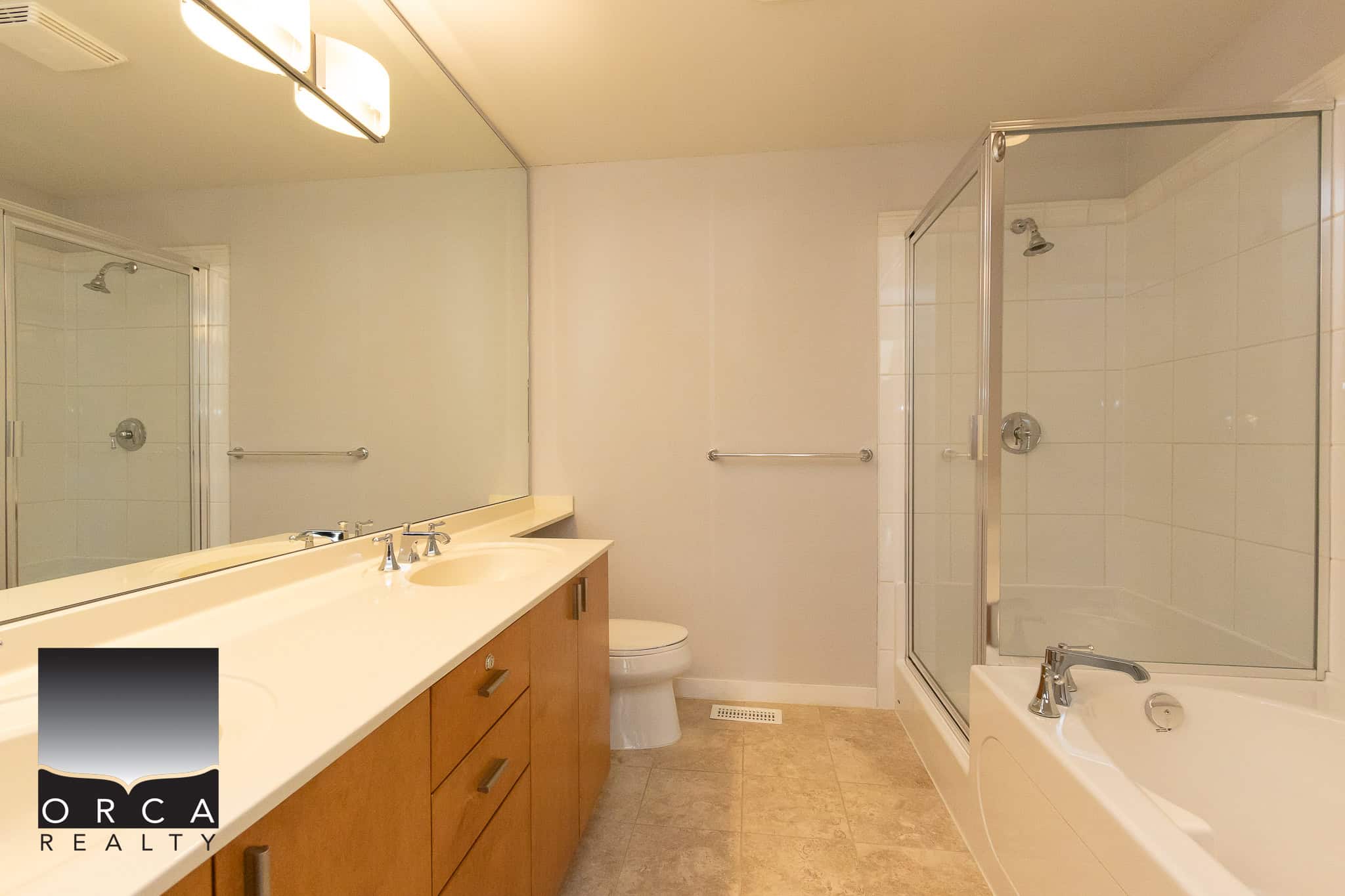 Bright bathroom with modern fixtures, spacious bathtub, and shower area, featuring neutral tones and ample storage, ideal for Vancouver real estate buyers seeking comfort and style.