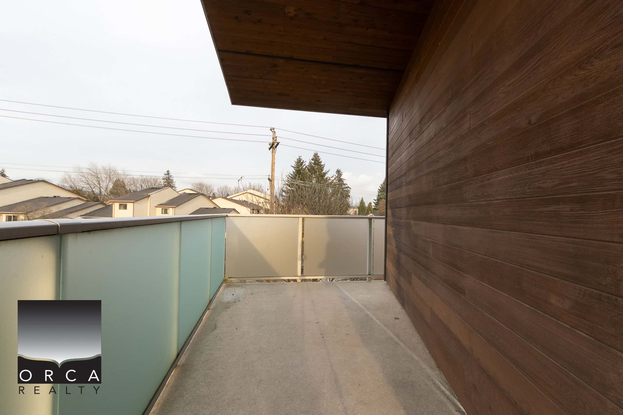 Modern balcony with frosted glass railing and wood-paneled exterior wall, ideal for outdoor living in Vancouver.