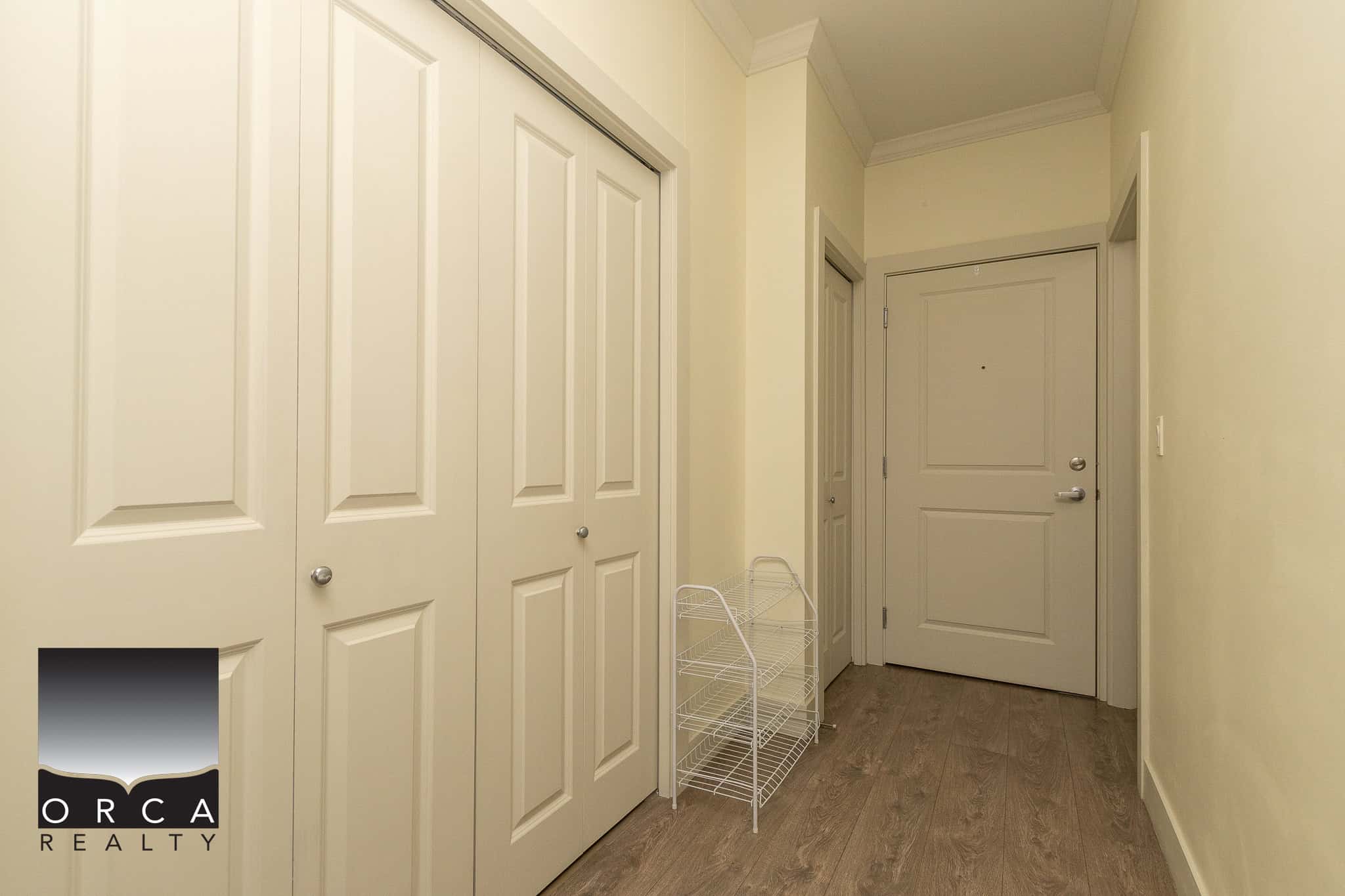 Bright residential hallway featuring ample closet space with double white doors, neutral wall colours, and a modern wooden floor; ideal for Vancouver-area apartment or condo listings.