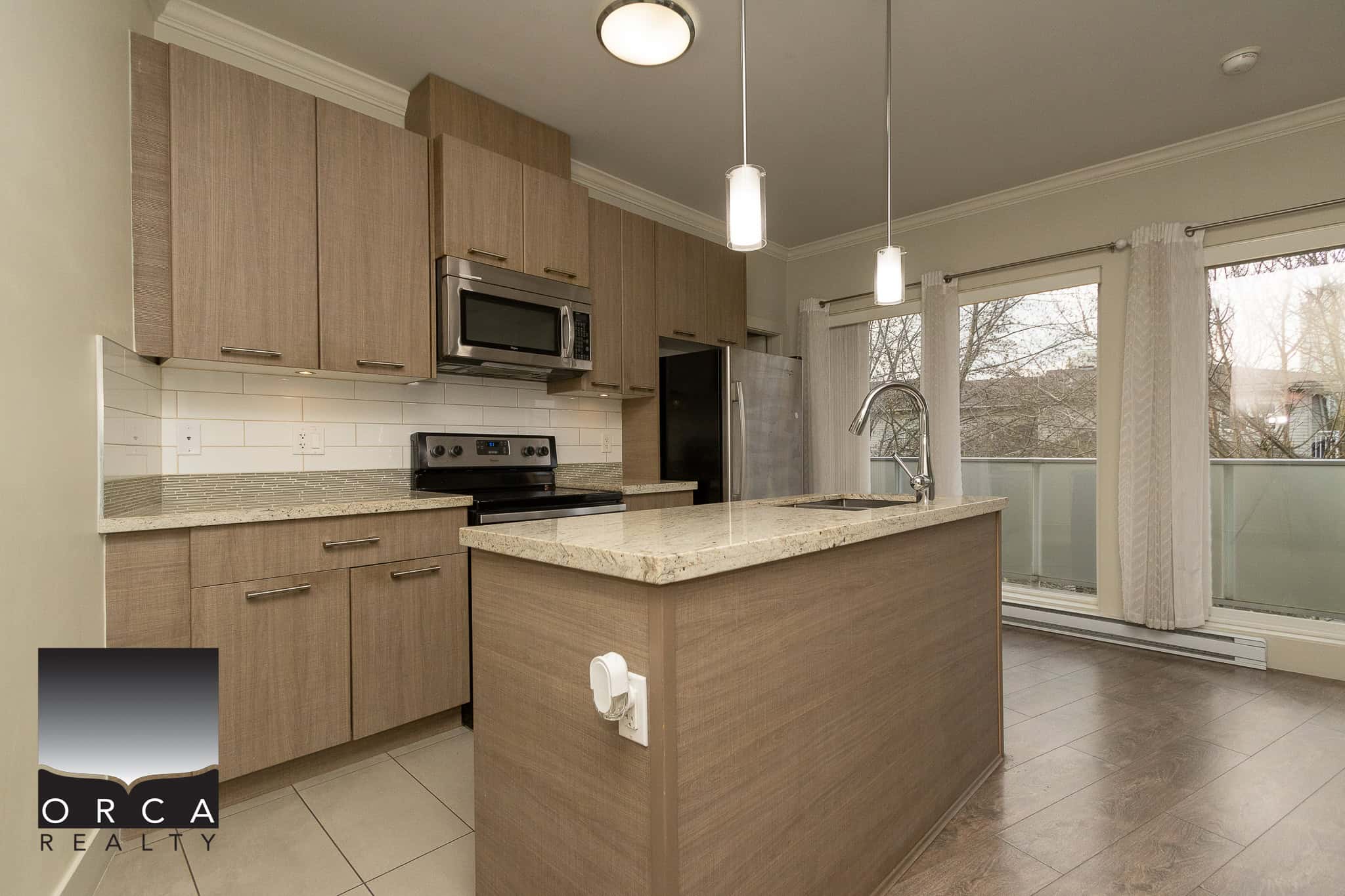 Modern kitchen with wood cabinets, stainless steel appliances, granite countertops, ample natural light from large windows, ideal for Vancouver Island real estate.