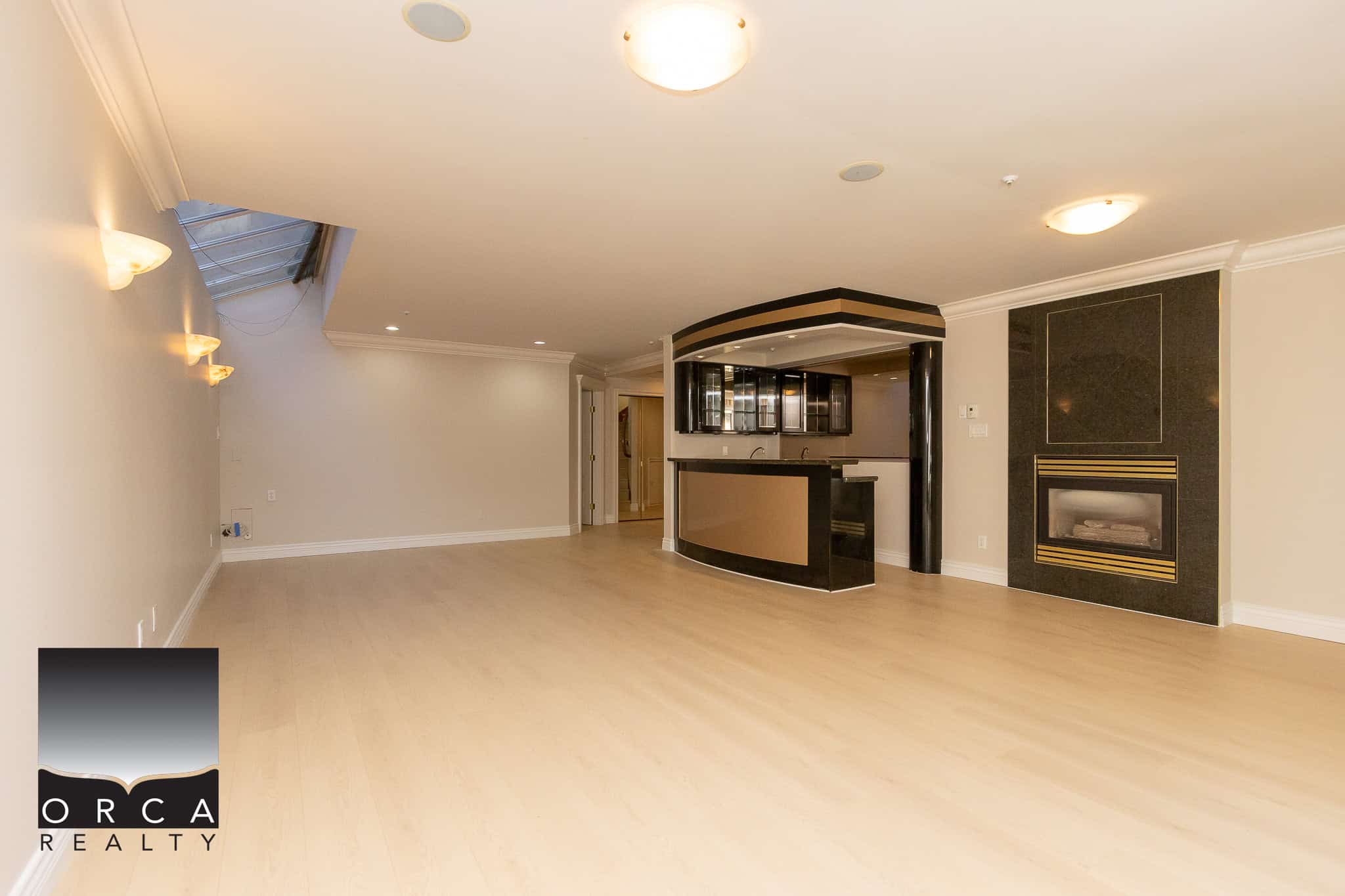 27 Spacious open-concept living area with modern kitchen, hardwood floors, and cozy fireplace, ideal for Vancouver Island homes or condos. Perfect for real estate listings showcasing elegant interior spaces.