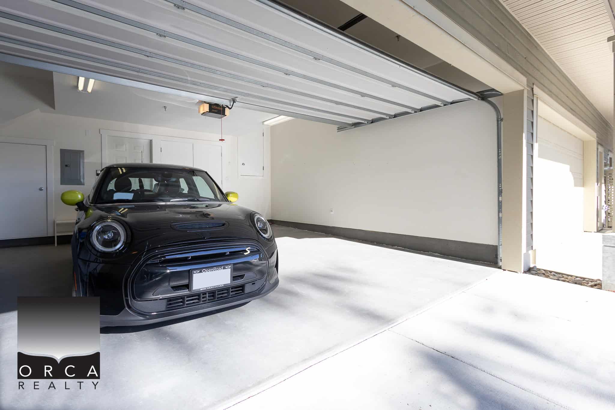 Black Mini Cooper parked inside a spacious, clean garage with enhanced natural lighting, perfect for secure vehicle storage.