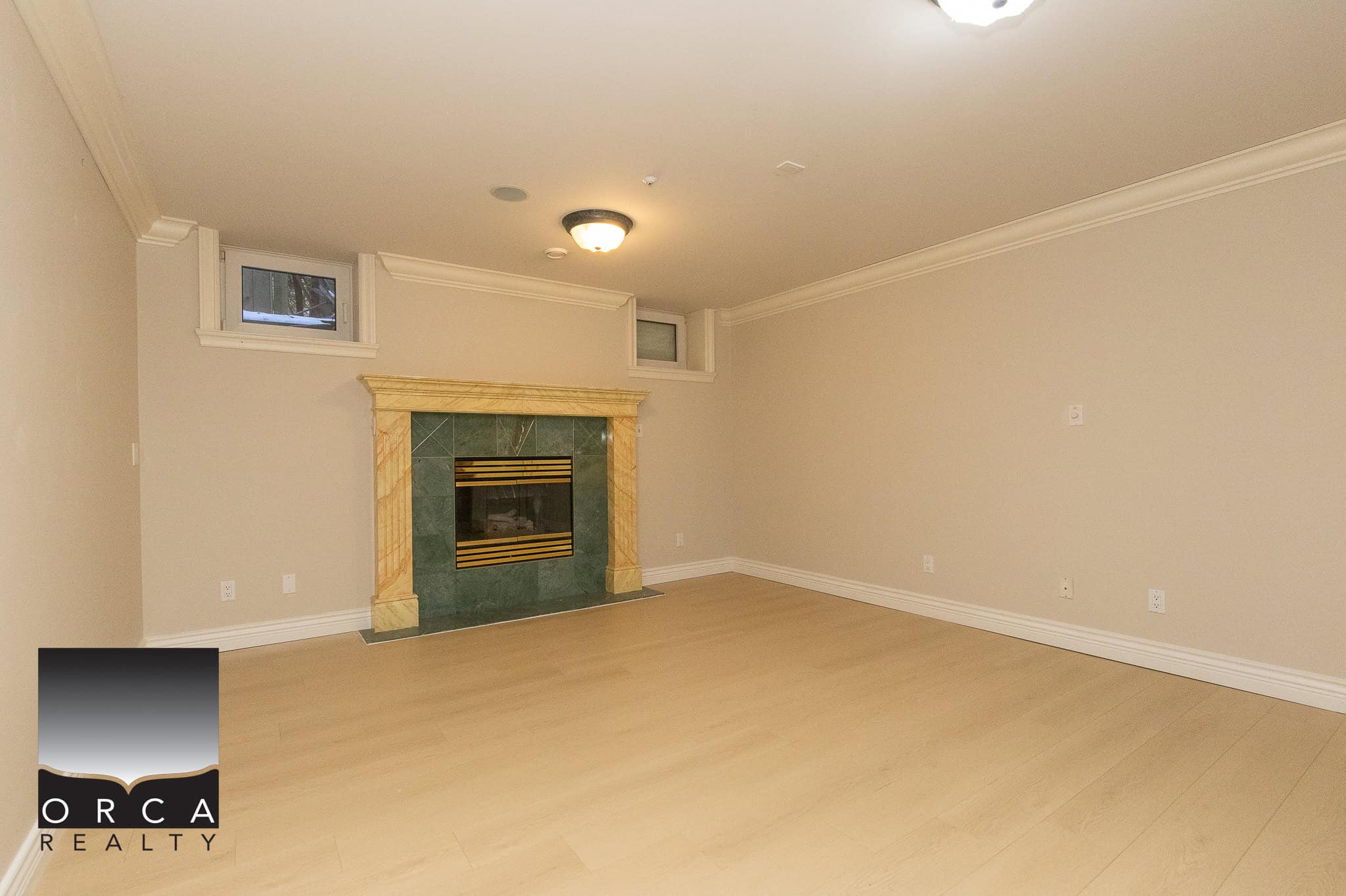 30 Spacious living room with a warm fireplace, light wood flooring, and neutral walls, perfect for family gatherings and relaxing in a beautiful home listed by Orca Realty Inc.