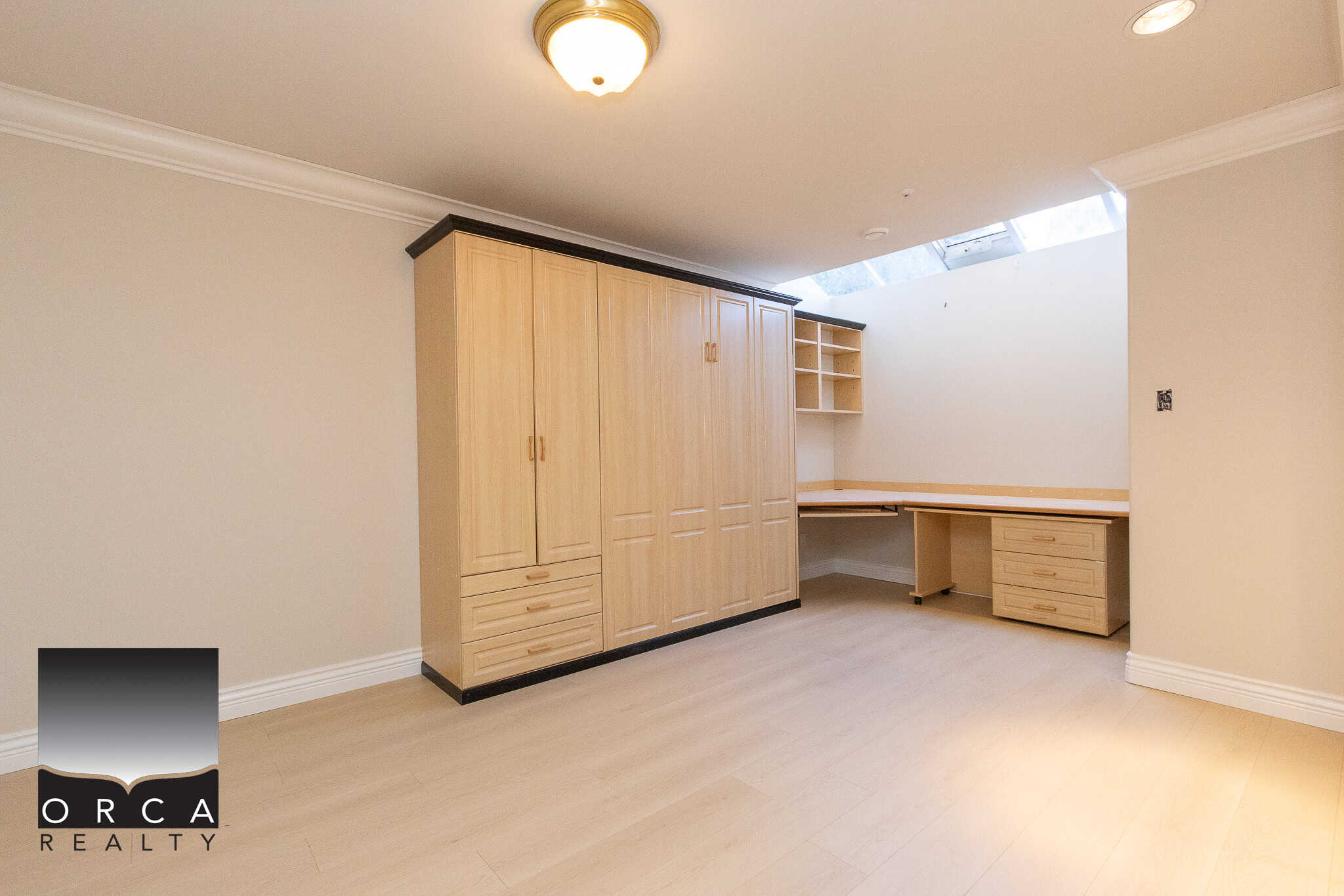 32 Spacious home office or bedroom with built-in wooden storage, desk, and cabinetry under a skylight, ideal for versatile living with modern design—perfect for Vancouver Island real estate.