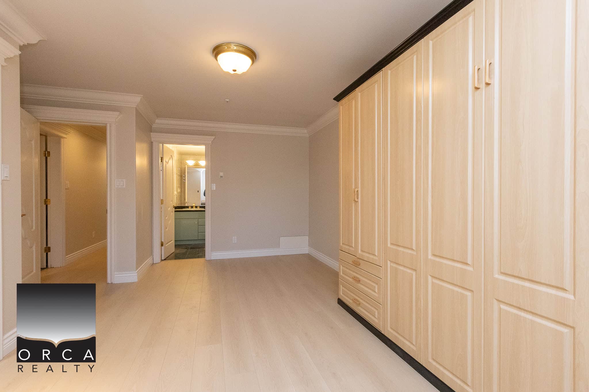 33 Open concept bedroom with light wood flooring, built-in wardrobe, neutral wall colors, and adjacent bathroom - perfect for Vancouver-area real estate buyers.