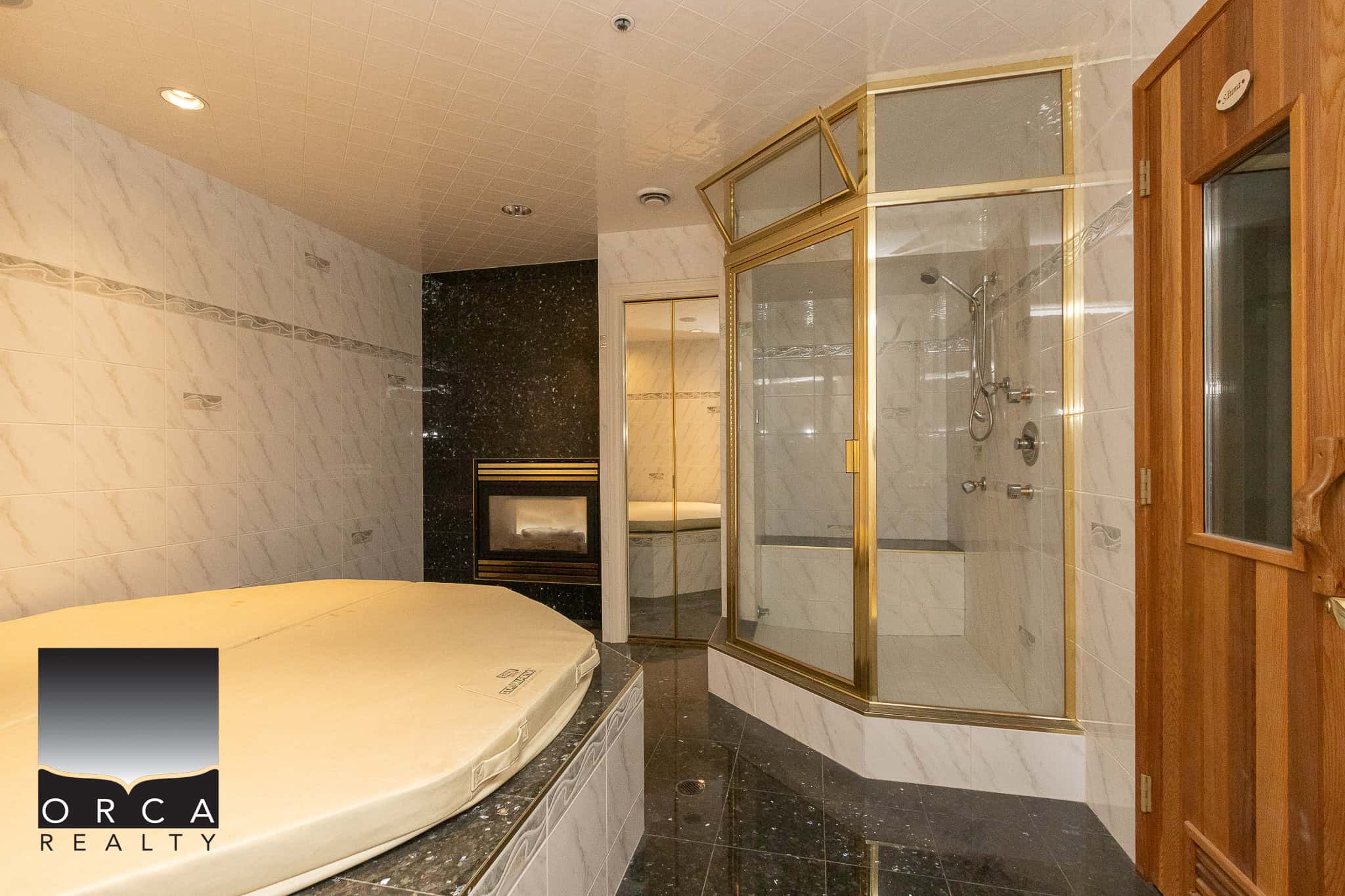36 Luxurious bathroom with marble tiles, glass shower enclosure, and a built-in fireplace, showcasing upscale real estate features from Orca Realty Inc. in a stunning residential property.