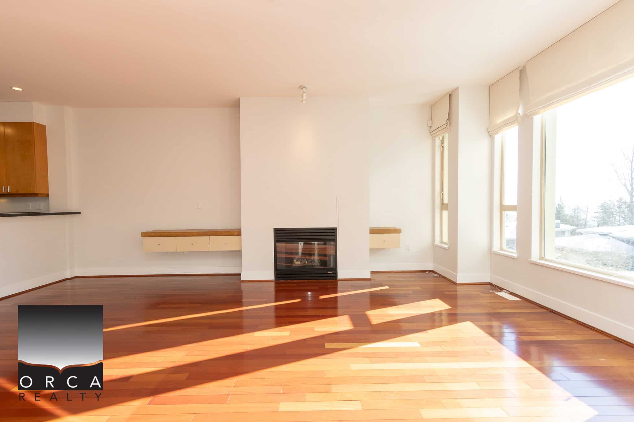 Bright living room interior with large windows, hardwood flooring, and a modern fireplace, ideal for homebuyers seeking comfortable and stylish properties in Vancouver.