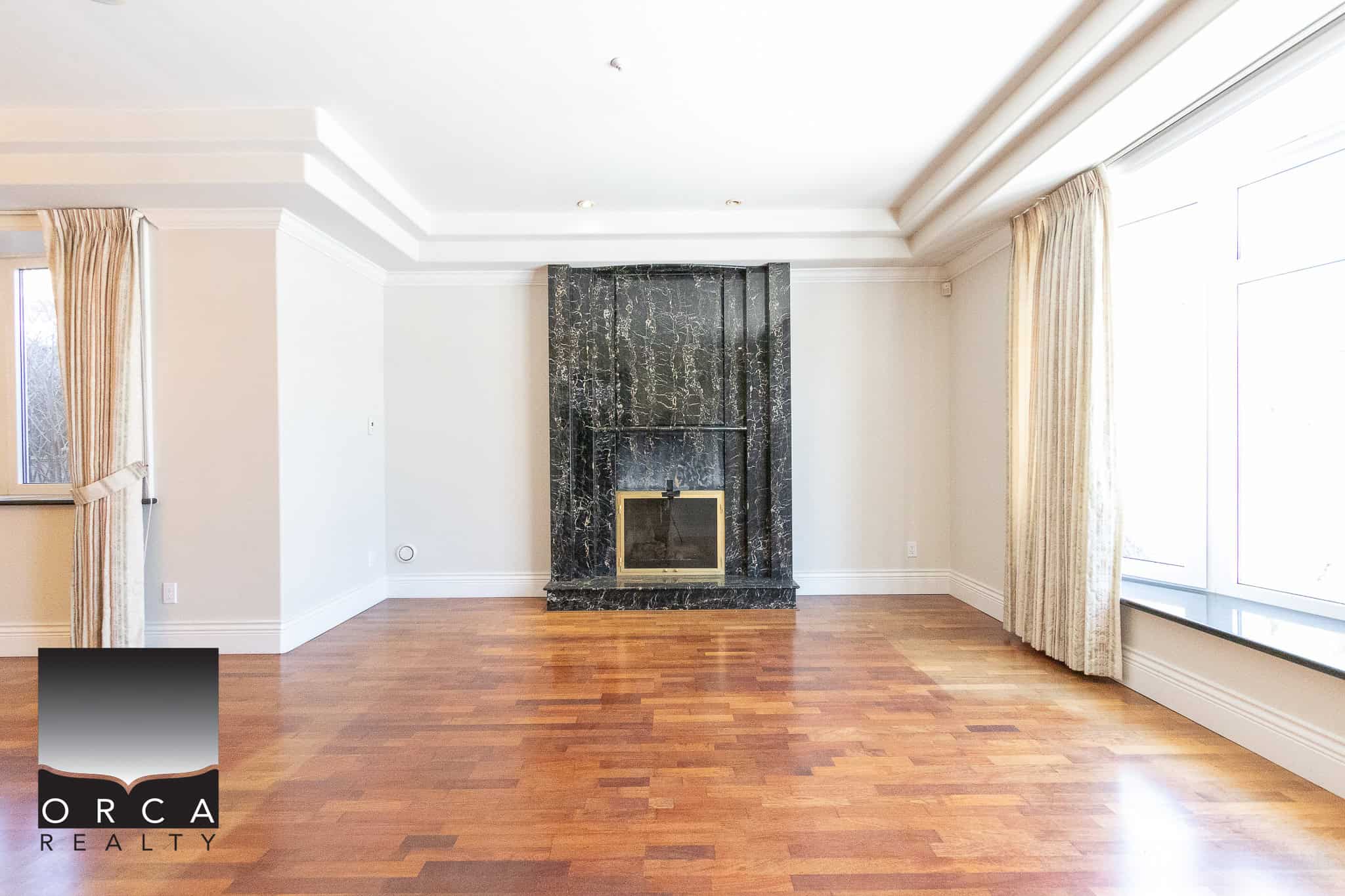 4 Modern living room with a black marble fireplace and hardwood floors, brightened by large windows with elegant curtains, ideal for Vancouver and Greater Vancouver real estate markets.