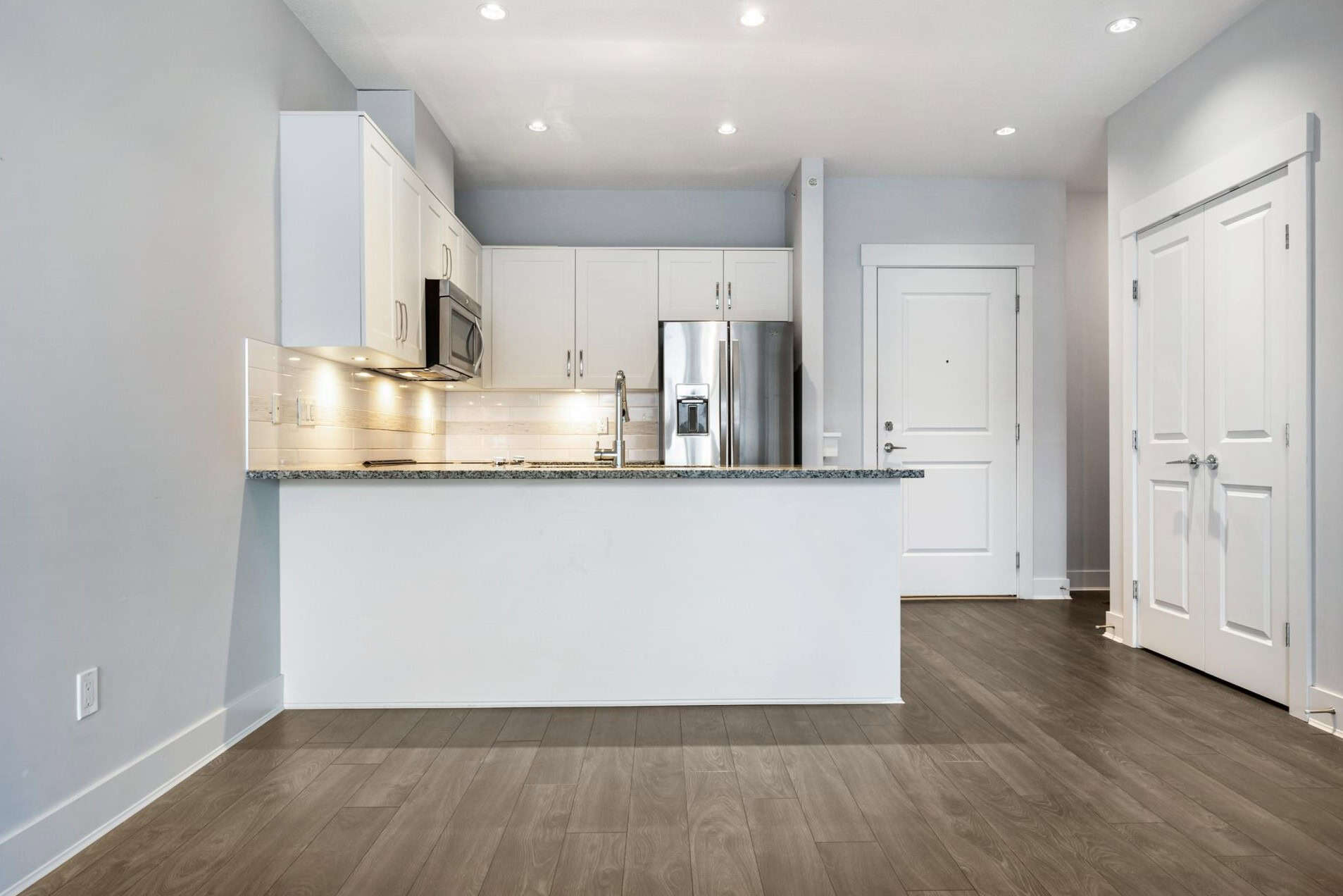 Bright modern kitchen with white cabinets, stainless steel appliances, granite countertops, and hardwood flooring, ideal for Vancouver and Greater Vancouver real estate listings.