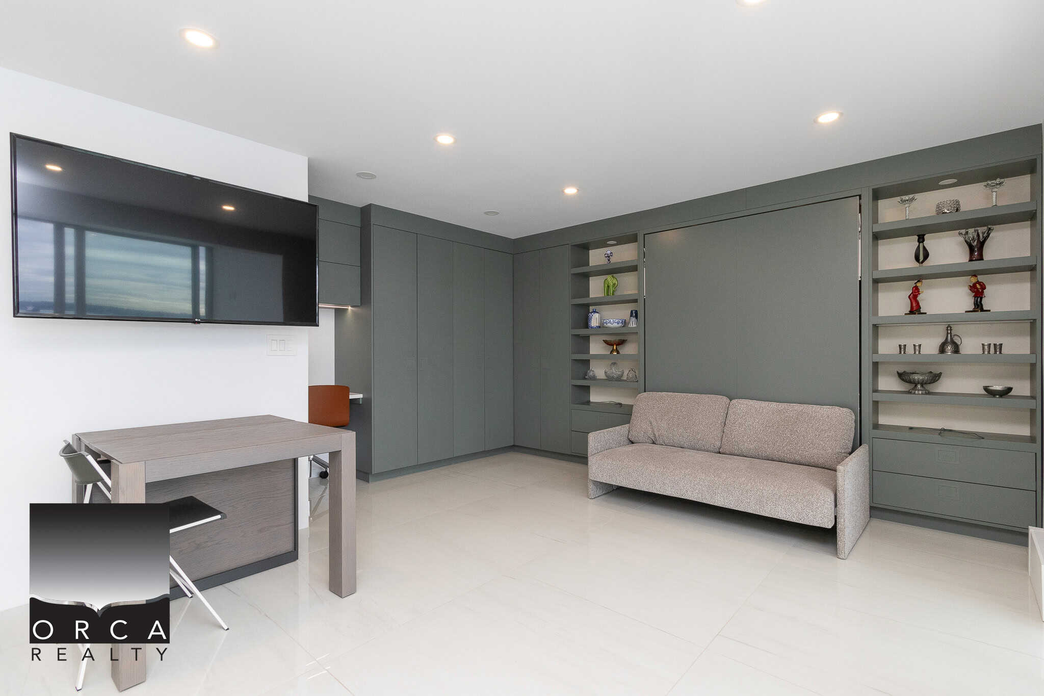Modern living room with grey built-in cabinetry, a comfortable grey sofa, and a large flat-screen TV, showcasing stylish home design for Vancouver real estate.