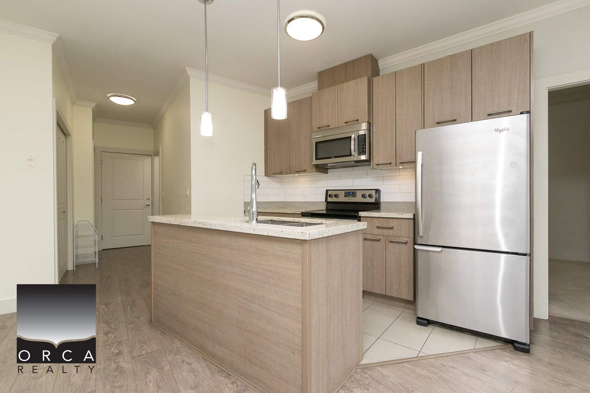 Modern open-concept kitchen with stainless steel appliances, granite countertops, and contemporary cabinetry, ideal for Vancouver real estate buyers seeking stylish homes.