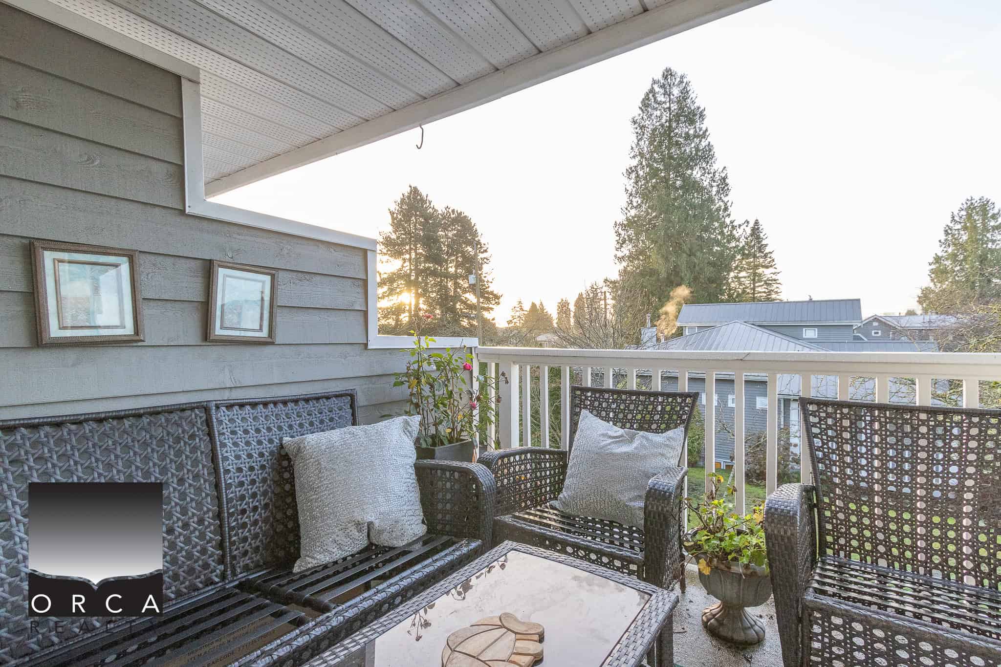Cozy outdoor balcony with wicker furniture and potted plants, offering a relaxing space to enjoy Vancouver Island's natural surroundings and scenic mountain views.