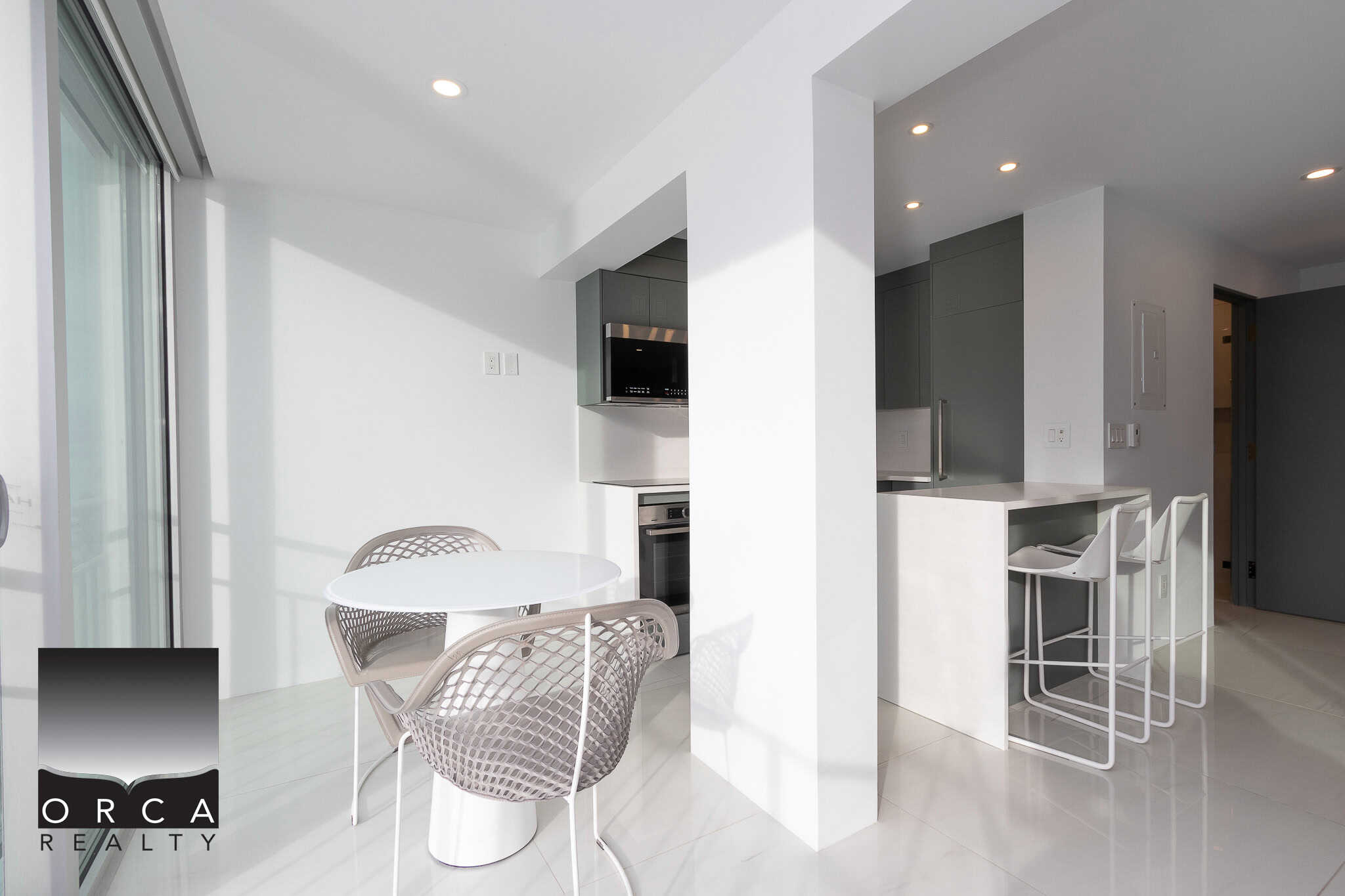 Bright modern kitchen and dining area with sleek white surfaces, minimalist design, and ample natural light, perfect for contemporary Vancouver real estate living.