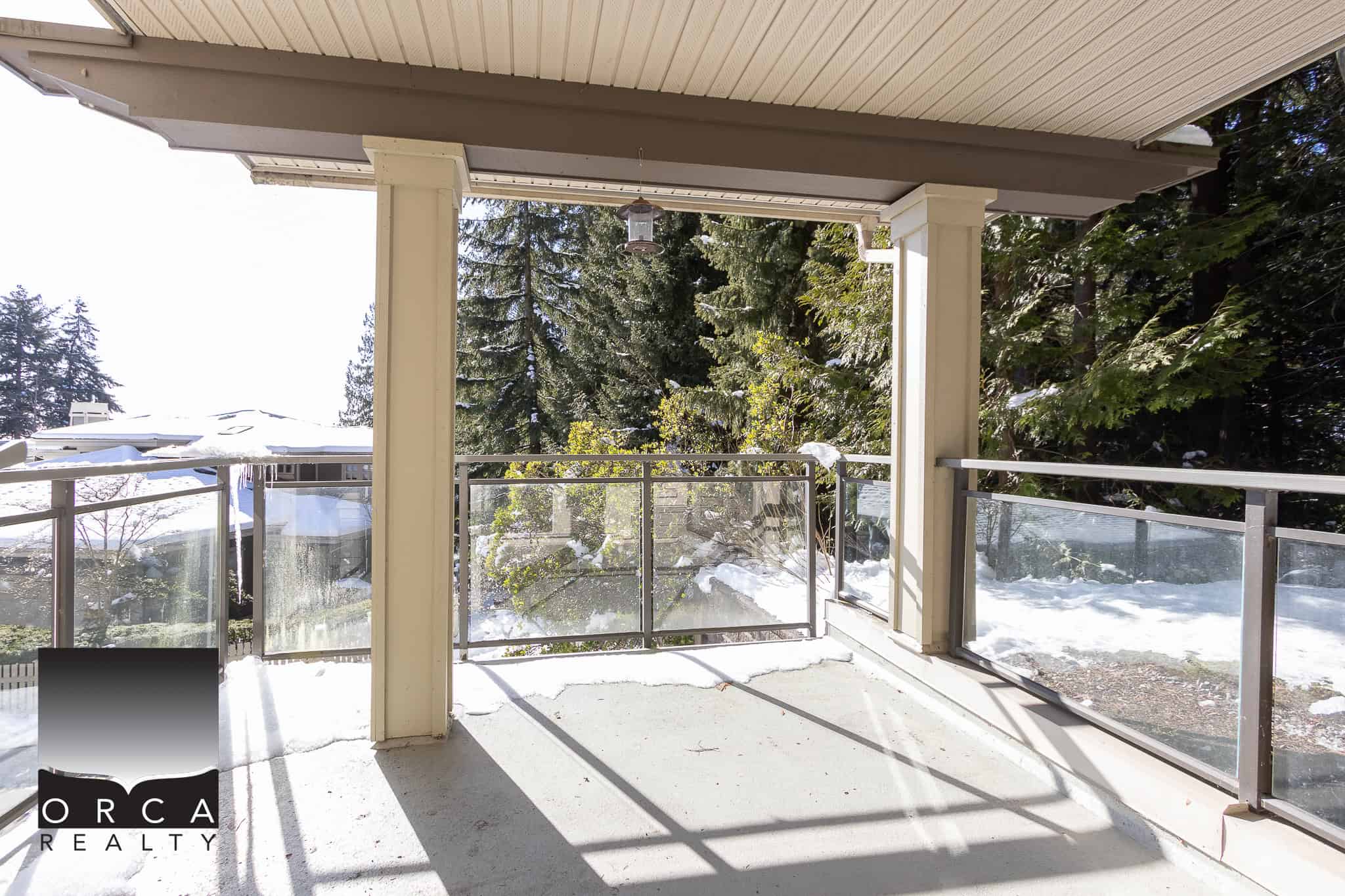 Bright balcony with snow and scenic forest view, ideal for relaxing or entertaining, showcasing the spacious outdoor living area of a home listed by Orca Realty Inc.