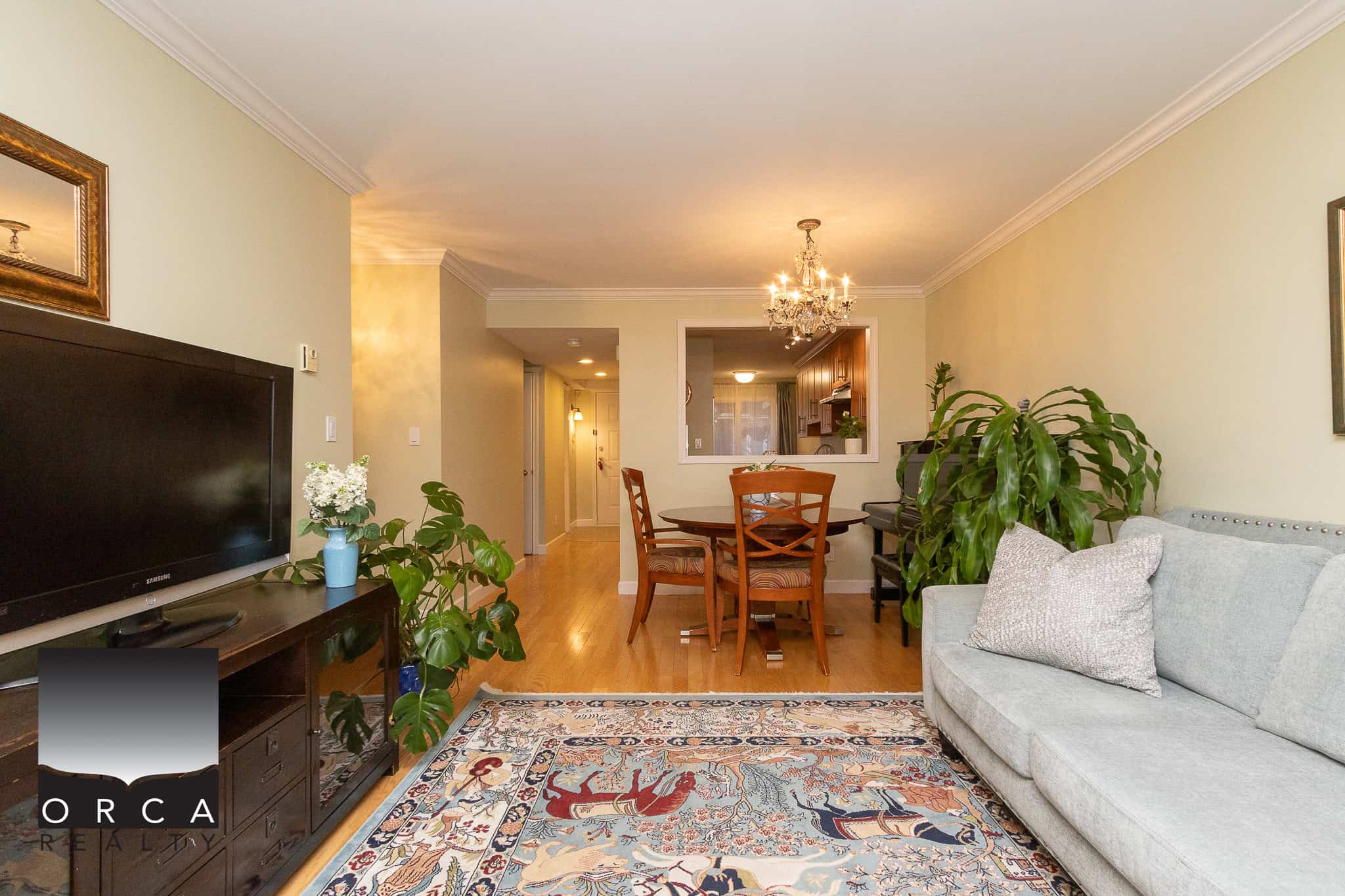 Bright and cozy living room interior with wooden flooring, comfortable sofa, and vibrant area rug, offering a welcoming space in a Vancouver-area home listed by Orca Realty Inc.