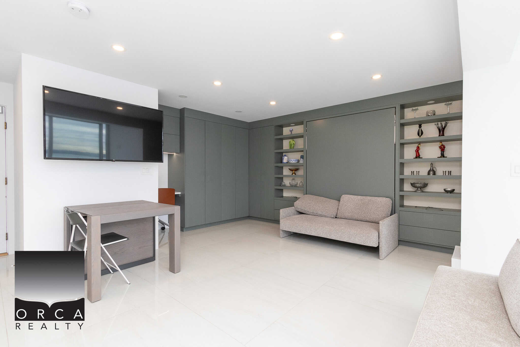 Modern living room with built-in grey cabinetry, minimalist decor, and a wall-mounted flat-screen TV, showcasing contemporary interior design ideal for Vancouver real estate listings.